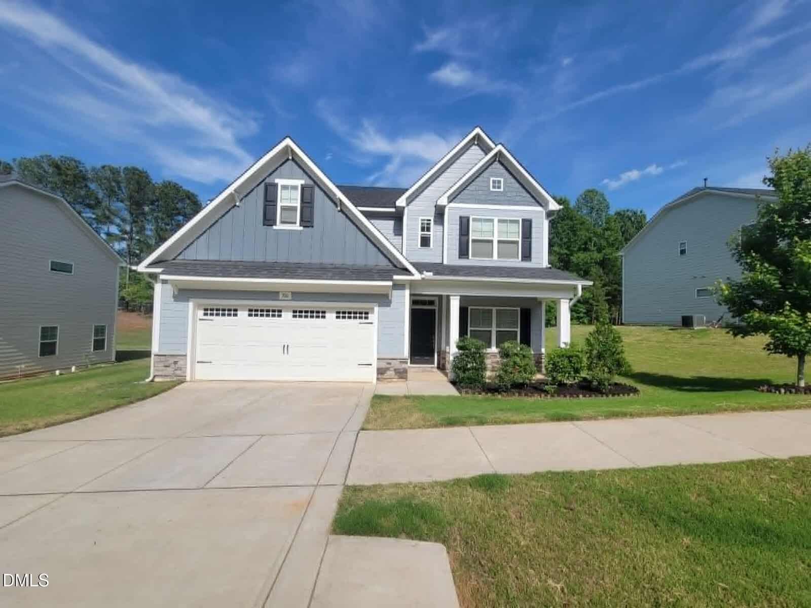 Two-story modern suburban house at 300 Olde Liberty Drive, Youngsville, with gray siding, white trim, a double garage, and a covered front porch on a spacious lawn, surrounded by neighboring homes under a blue sky.