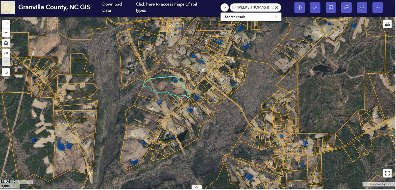 A satellite map of Granville County, NC, displays property boundaries outlined in yellow, scattered buildings in blue, roads, and wooded areas. A specific parcel is highlighted in light blue near the center of the image.