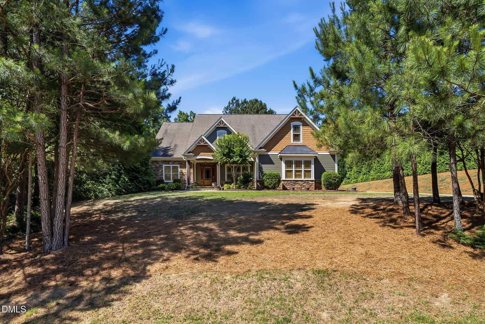 A large house with a gray roof and wooden accents sits surrounded by trees at 90 Pebble Creek Drive, Franklinton. The front lawn is mostly dry with patches of brown grass, and a driveway leads to the entrance under a clear blue sky.