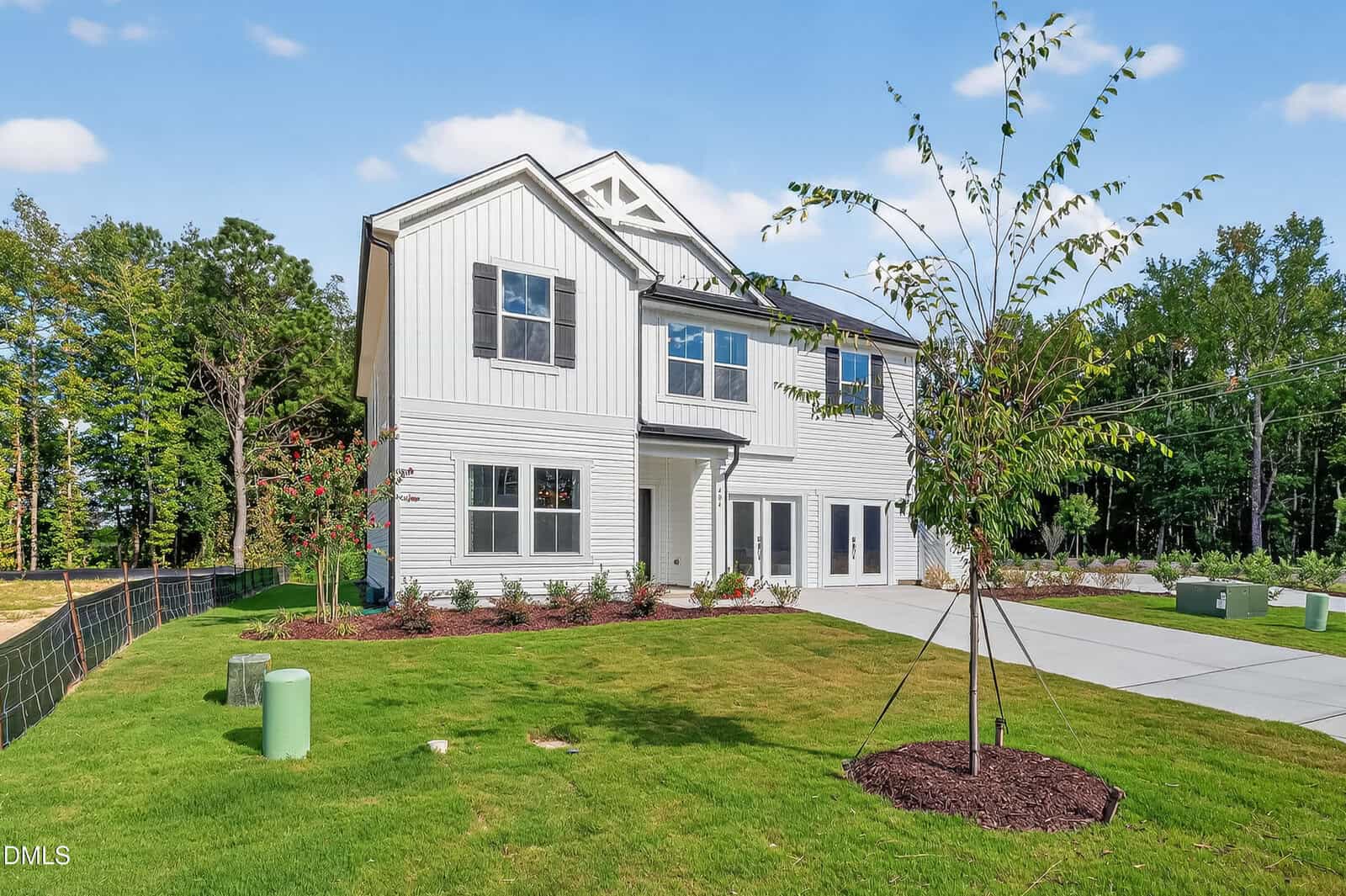Two-story modern house at 102 Airdale Drive, Oxford, with a white exterior, large windows, and dark trim, surrounded by a green lawn, young trees, and a clear driveway on a sunny day with blue sky.