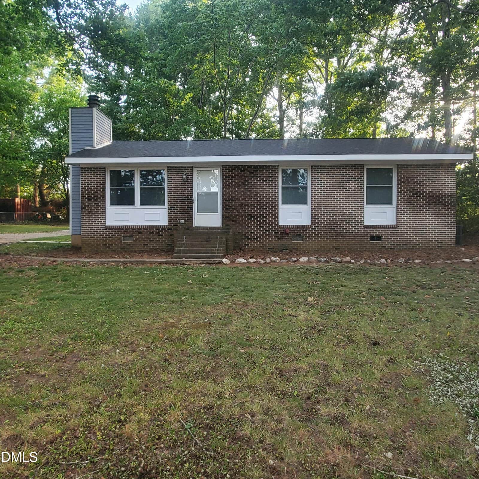 Charming single-story brick house at 443 Park Avenue, Youngsville, featuring three front windows, a central door, and a cozy front porch. Surrounded by grass and trees with a wooded area in the background.