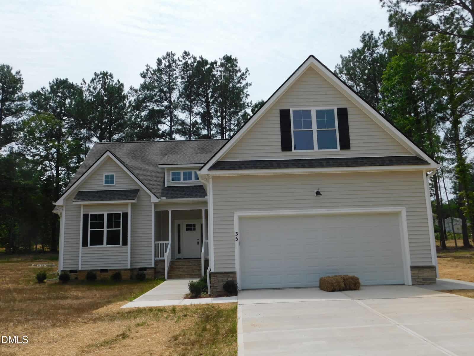 A modern two-story beige house at 35 Copper Penny Road in Zebulon, featuring a double garage, white trim, and a covered front porch. The front yard has dry grass and pine trees in the background.