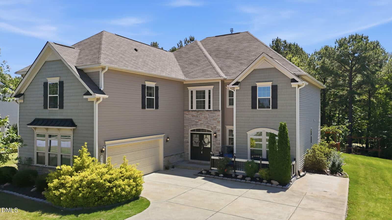 Charming two-story suburban house at 535 Long View Drive, Youngsville, featuring gray siding, stone accents, a two-car garage, and well-kept landscaping with shrubs and trees surrounding the driveway and spacious grassy backyard.