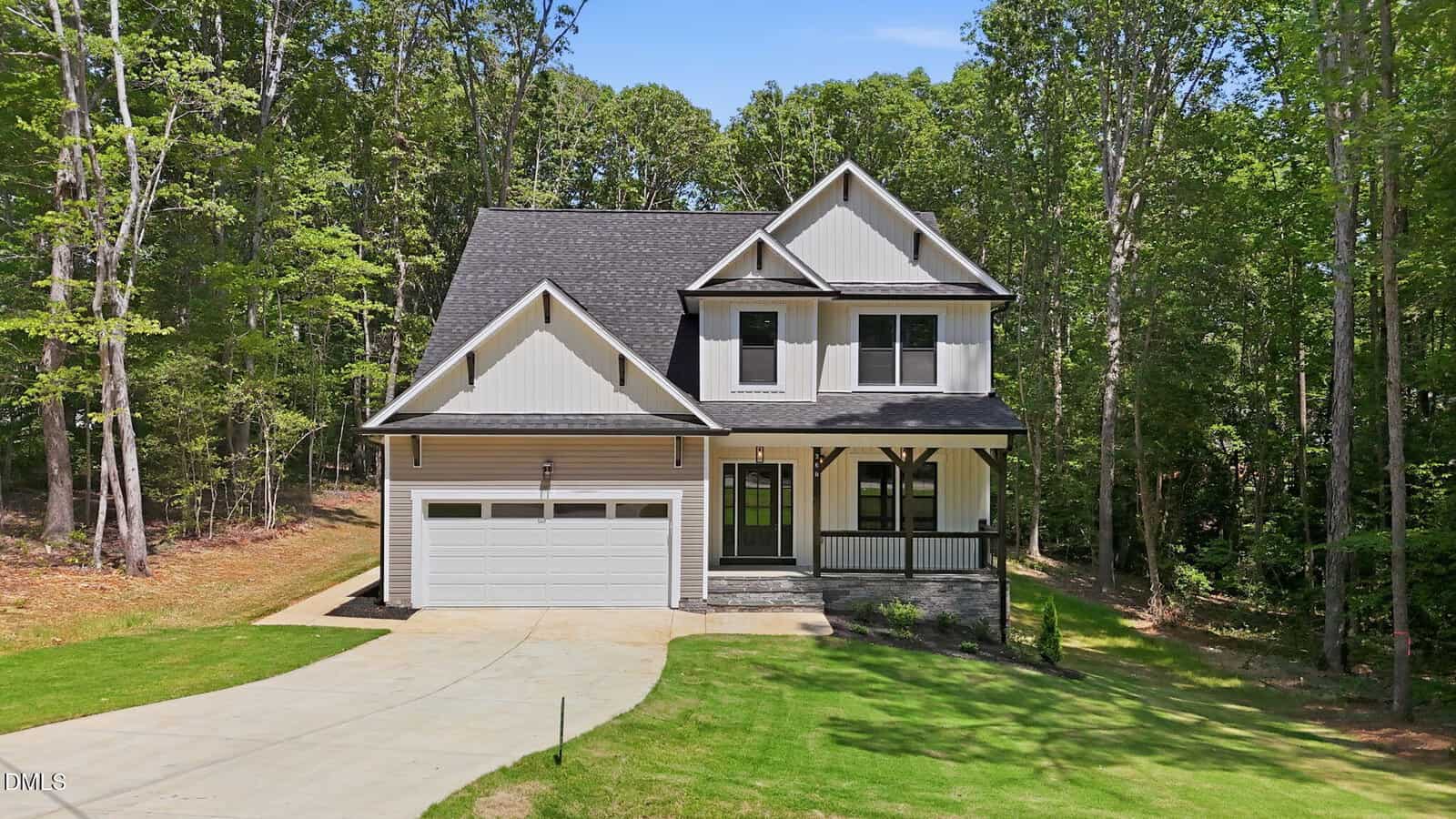 Two-story modern farmhouse at 627 Shawnee Drive in Louisburg features white siding, dark trim, a gable roof, covered front porch, and two-car garage, all nestled among trees and a well-kept lawn on a sunny day.