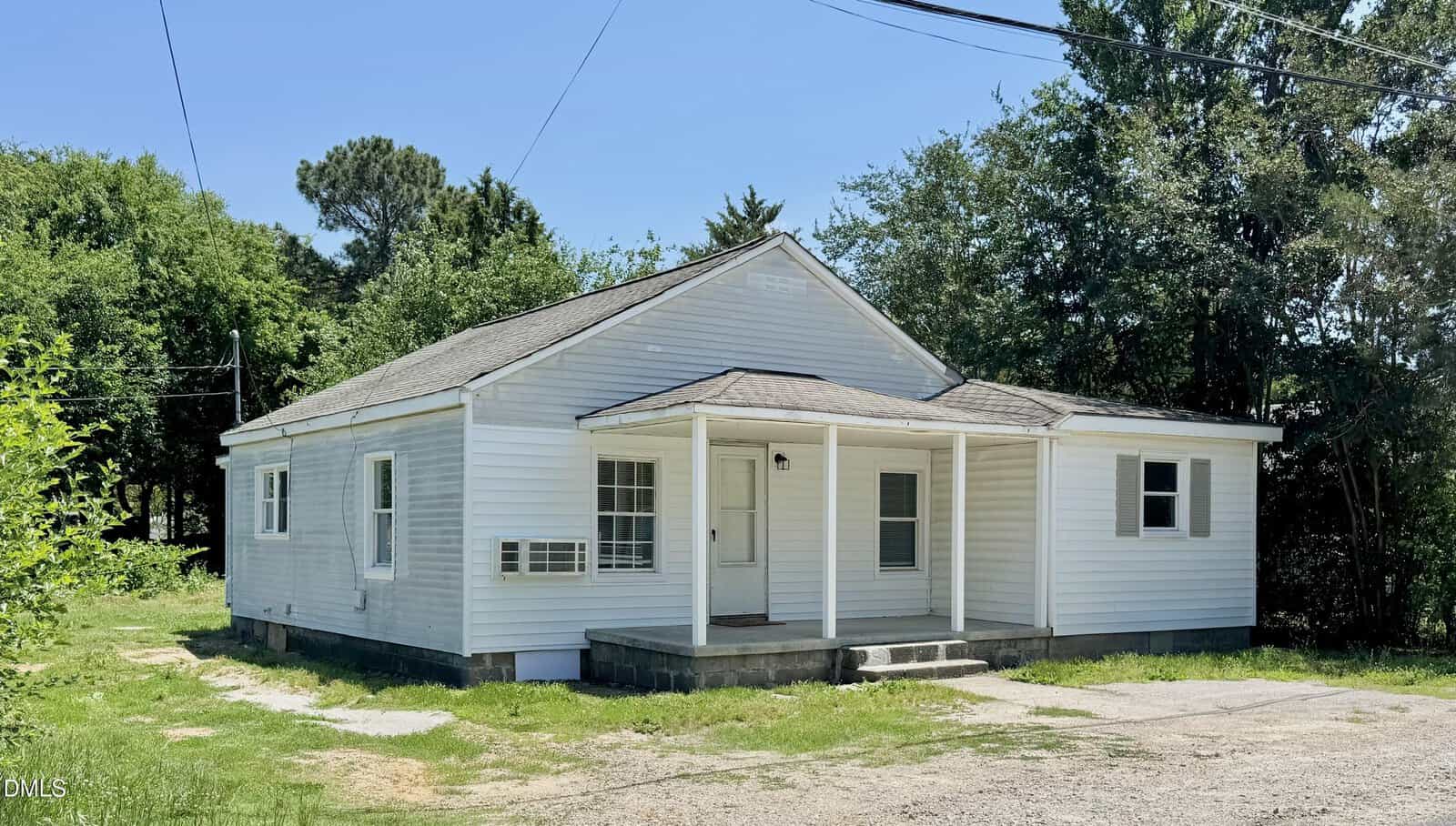 A small, single-story white house with a gabled roof, front porch, and concrete steps at 1246 Hight Street in Henderson, surrounded by grass, trees, and a paved driveway under a clear blue sky.