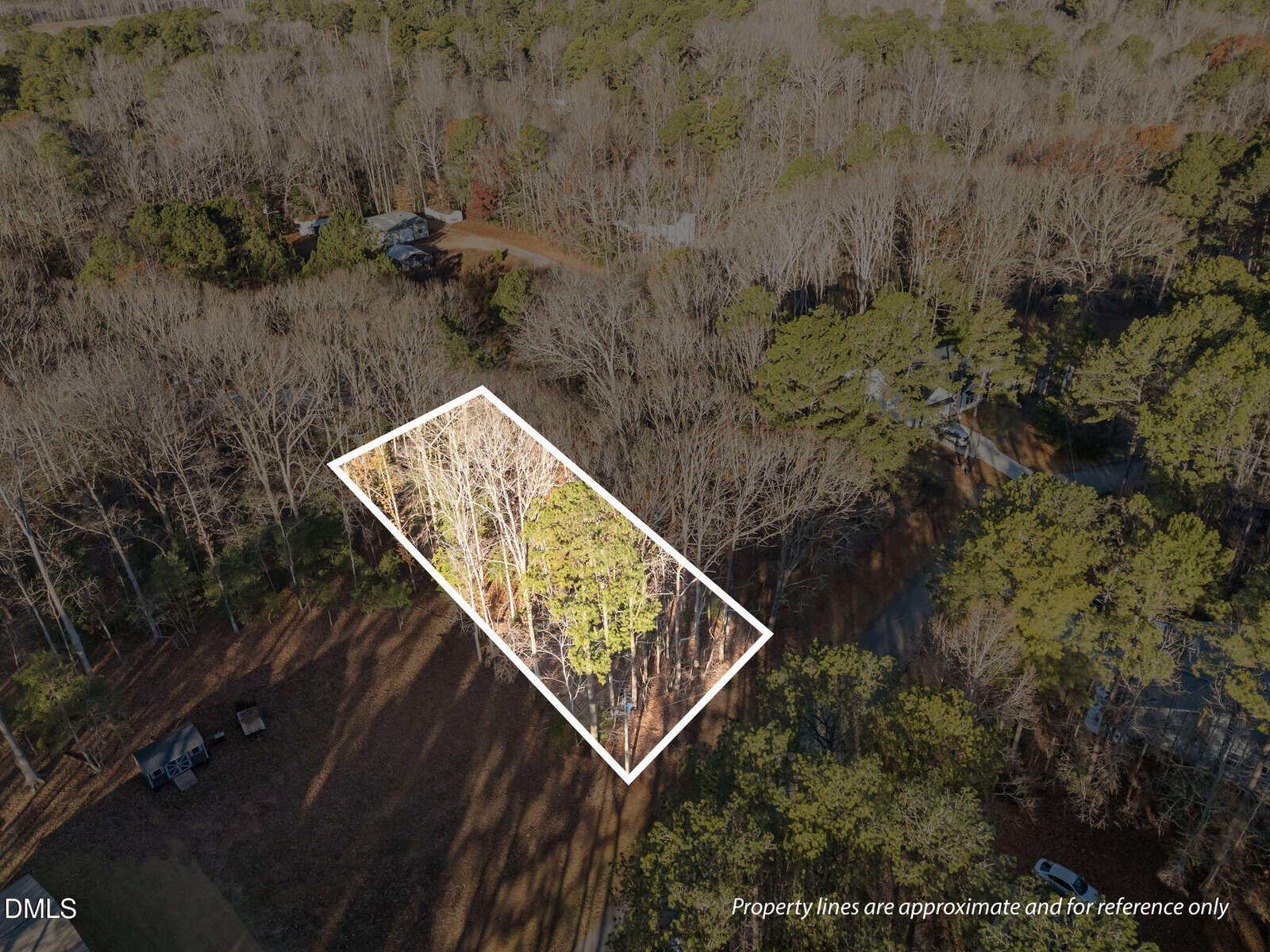 A rectangular plot of wooded land at 107 Wagon Wheel Circle, Louisburg, is shown from above in a forested area with nearby houses and roads. The property lines are outlined in white and noted as approximate.