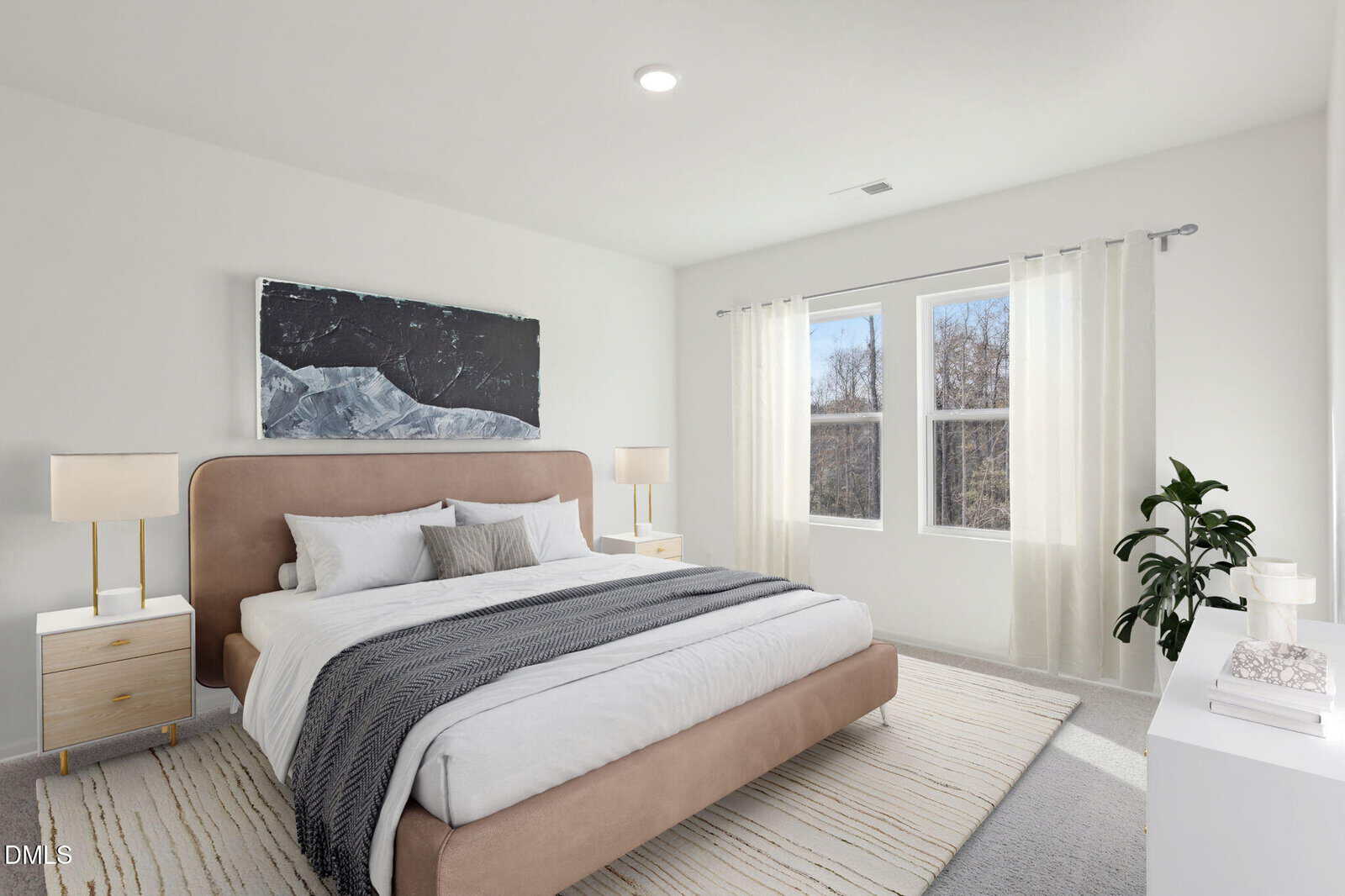 A modern bedroom with a beige upholstered bed, gray blanket, white bedding, two bedside tables with lamps, large windows with sheer curtains, a plant, and a black-and-white mountain artwork above the bed.