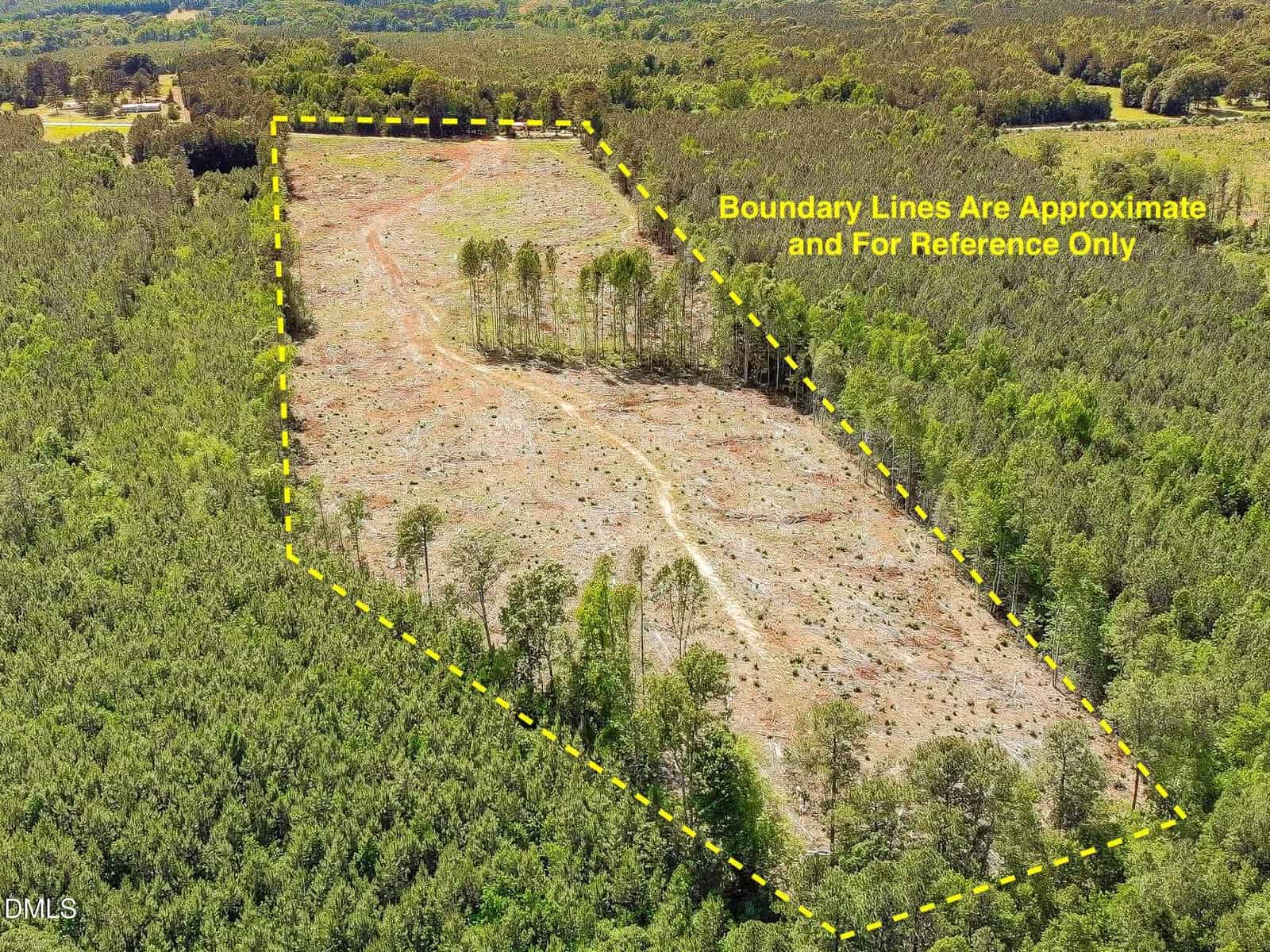 Aerial view of a cleared land plot in a forest, outlined with yellow dashed lines showing approximate boundaries; text notes lines are for reference only.