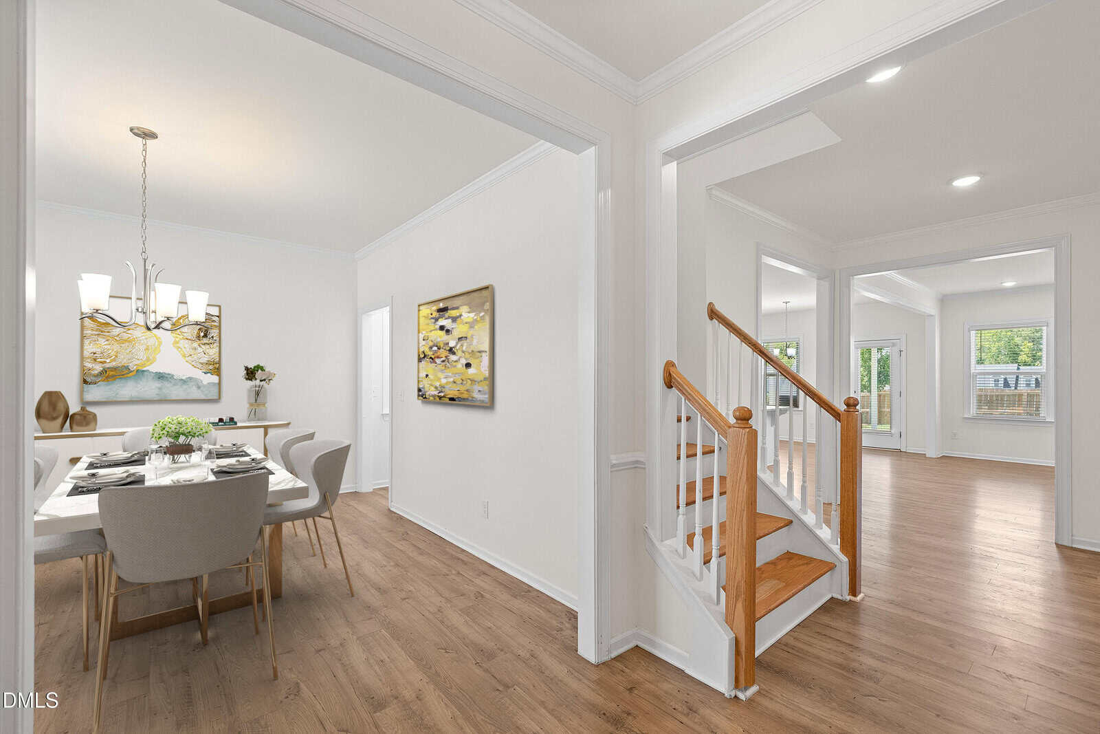 Bright, modern home interior with an open floor plan, featuring a dining area with a table and chairs, wooden staircase with white railing, and spacious living areas with wood floors and large windows.