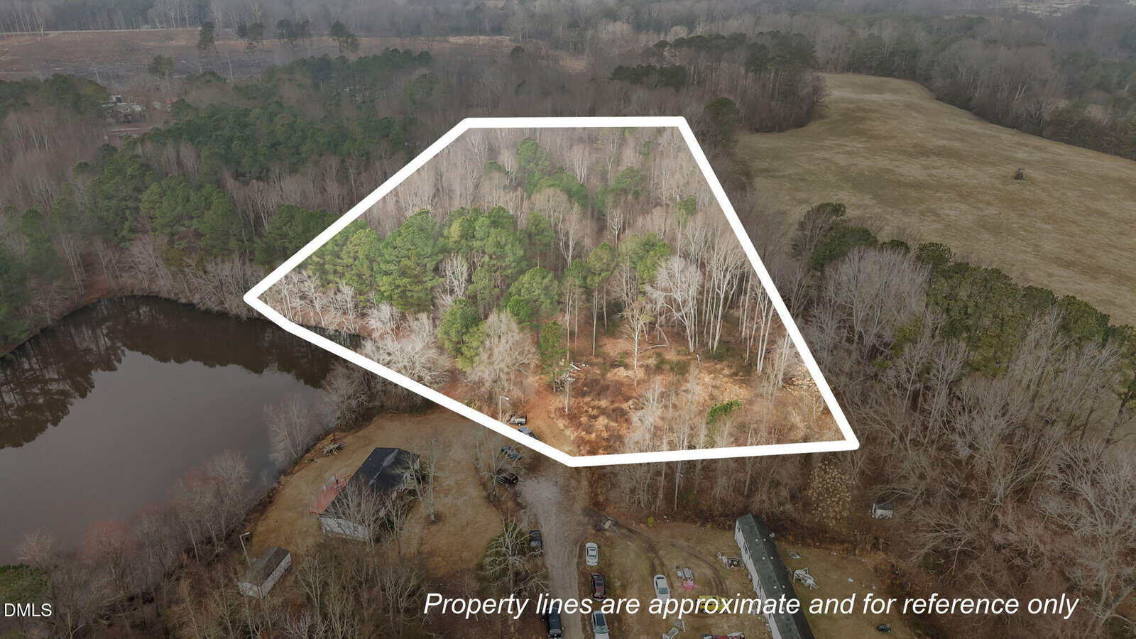 Aerial view of a wooded property at 120 Corinth Drive, Louisburg, outlined in white, showing dense trees, a nearby pond, open field, and several buildings. Text reads: "Property lines are approximate and for reference only.