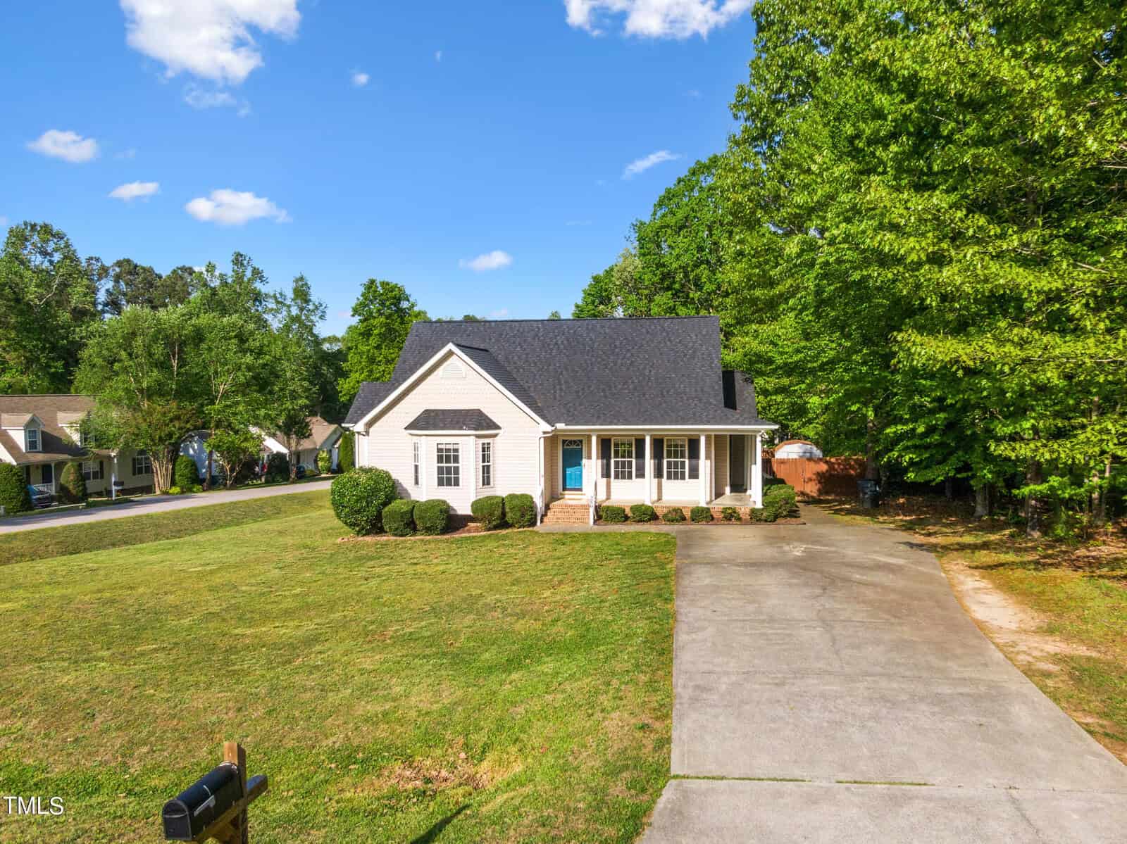 Charming single-story beige house at 280 Beaver Ridge Drive, Youngsville, with a dark roof and front porch, set back from the street with a wide driveway and well-kept lawn, surrounded by trees under a blue sky with scattered clouds.