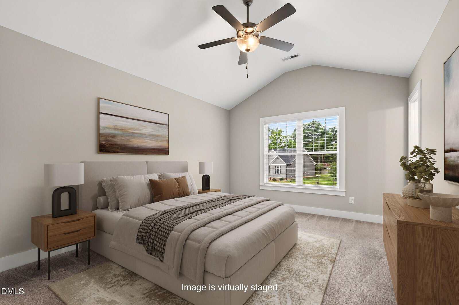 A virtually staged bedroom with a bed, two nightstands, lamps, a dresser, wall art, a rug, and a ceiling fan. A window shows green trees and houses outside. Neutral colors and simple decor dominate the space.