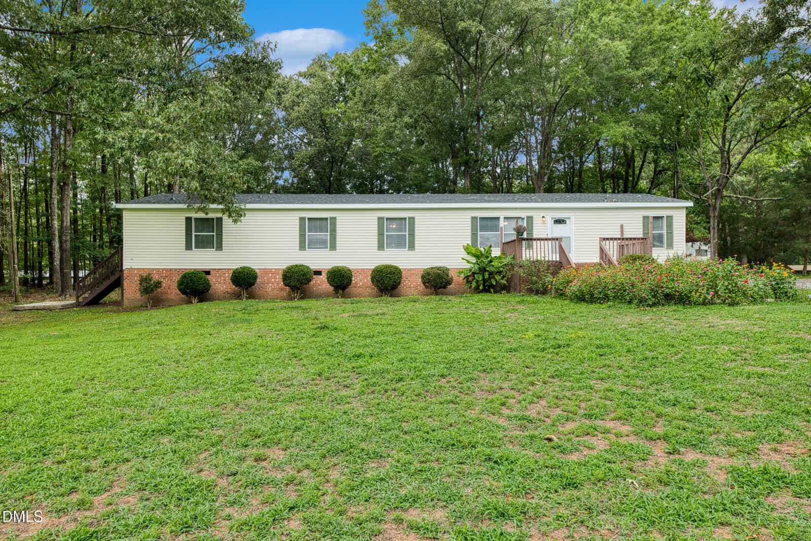 A white, single-story manufactured home with a brick foundation sits on a grassy lawn at 308 Allen Avenue in Franklinton, surrounded by green shrubs and trees under a partly cloudy sky.