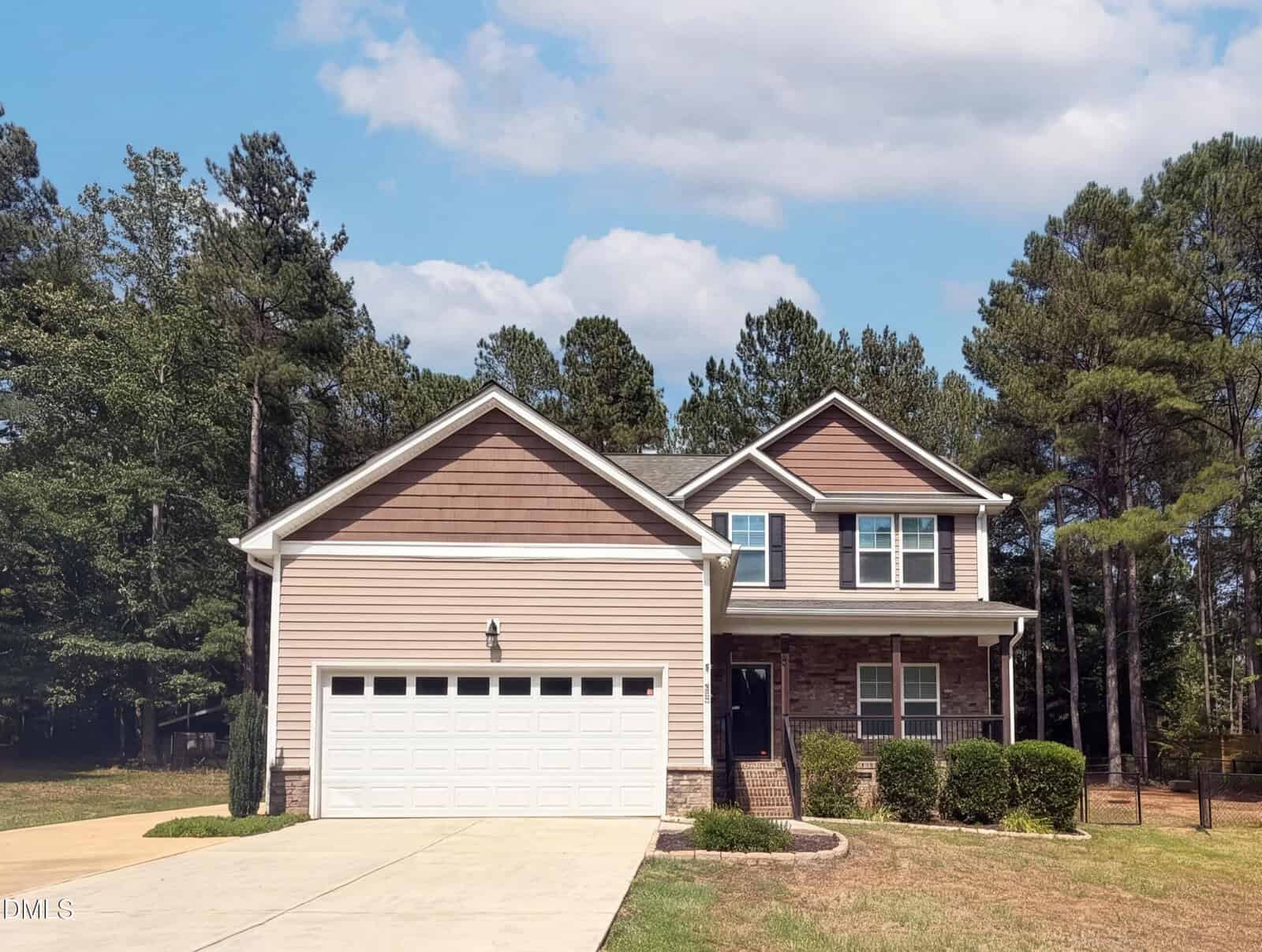 Charming two-story suburban house at 2137 Emerald Lane in Franklinton, with beige siding, brown accents, and a brick lower facade. Features a white double garage, driveway, small porch, and lush landscaping with green grass and tall trees.
