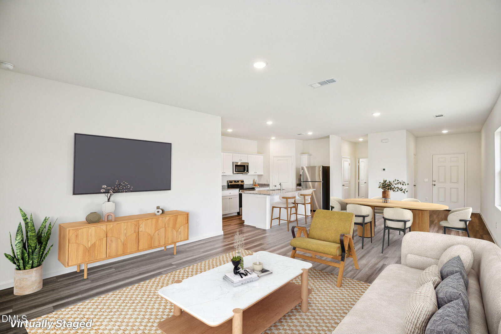 A bright, open living area with modern virtual furnishings, including a sofa, armchair, coffee table, TV console, and dining set. The space has wood floors, white walls, and a sleek kitchen in the background.