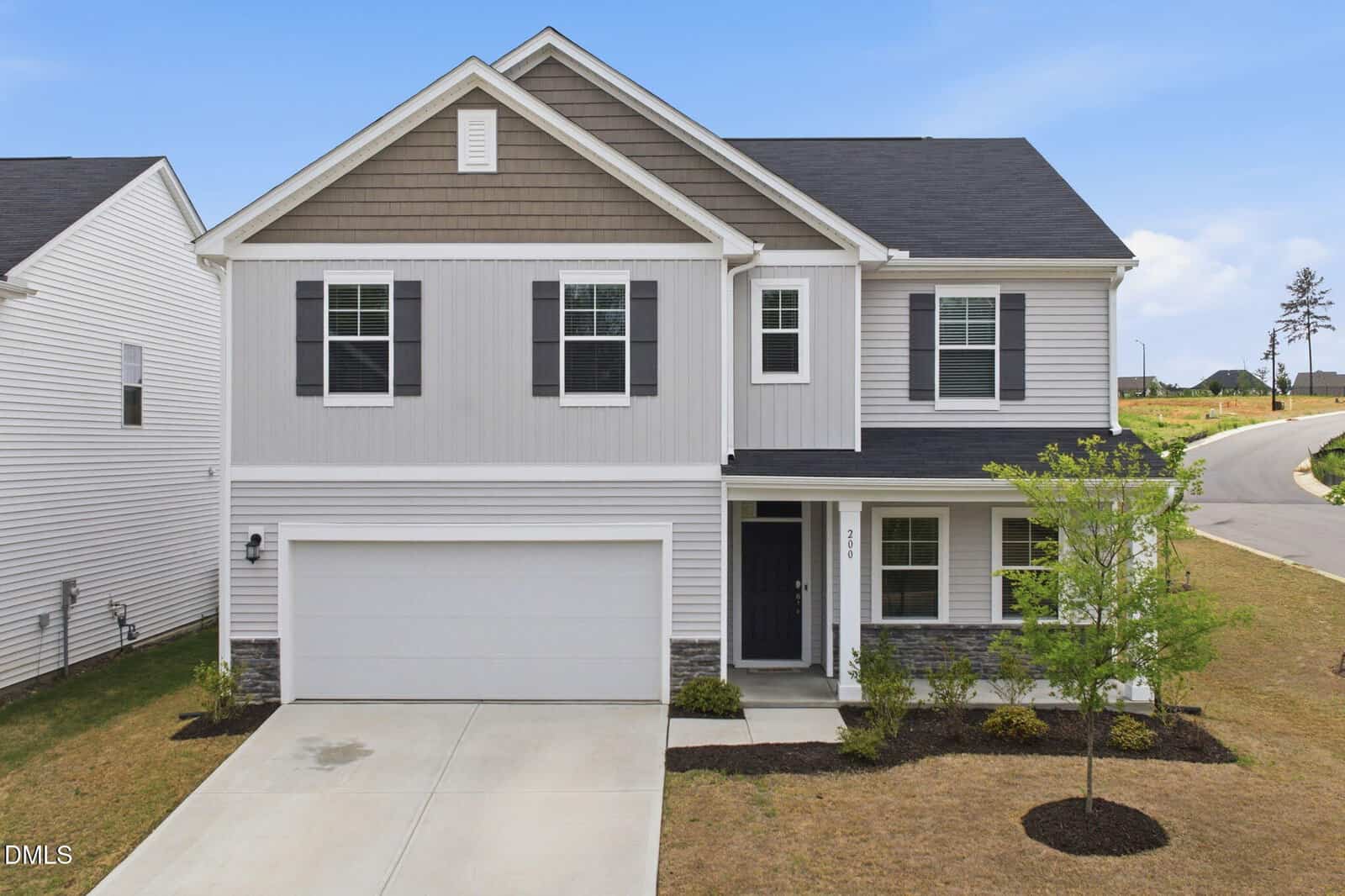 Charming two-story suburban house at 200 Carolina Maple Drive, Franklinton, with gray siding, white trim, and black shutters. Features a two-car garage, small front porch, minimal landscaping, young tree in the yard, and a clear sky.