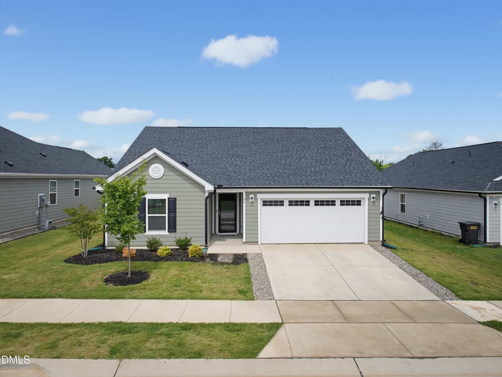 Single-story gray house with a dark roof, white trim, attached two-car garage, small front porch, and landscaped yard with a young tree at 95 Button Bush Lane in Youngsville, viewed from the street on a clear day.