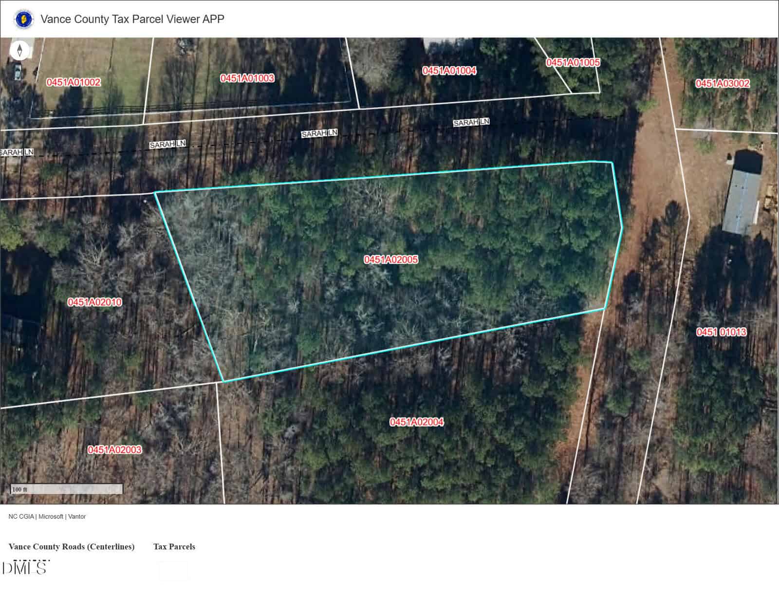 Aerial view of a wooded land parcel outlined in blue, surrounded by other parcels with red boundary lines and numbers. Some structures and roads are visible nearby. The map is labeled "Vance County Tax Parcel Viewer APP.