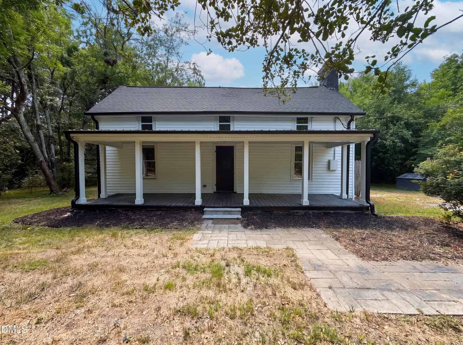 A white, two-story house with a covered front porch and a black door at 571 Winston Street in Franklinton, surrounded by trees and patchy grass. Stone pavers lead up to the porch under a partly cloudy sky.