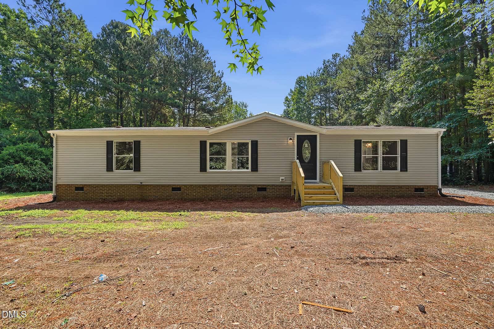 Charming single-story beige house with dark shutters at 2554 Conyers Road, Franklinton. Features a front porch and steps, set in a spacious yard with pine needles and tall trees under a clear blue sky.