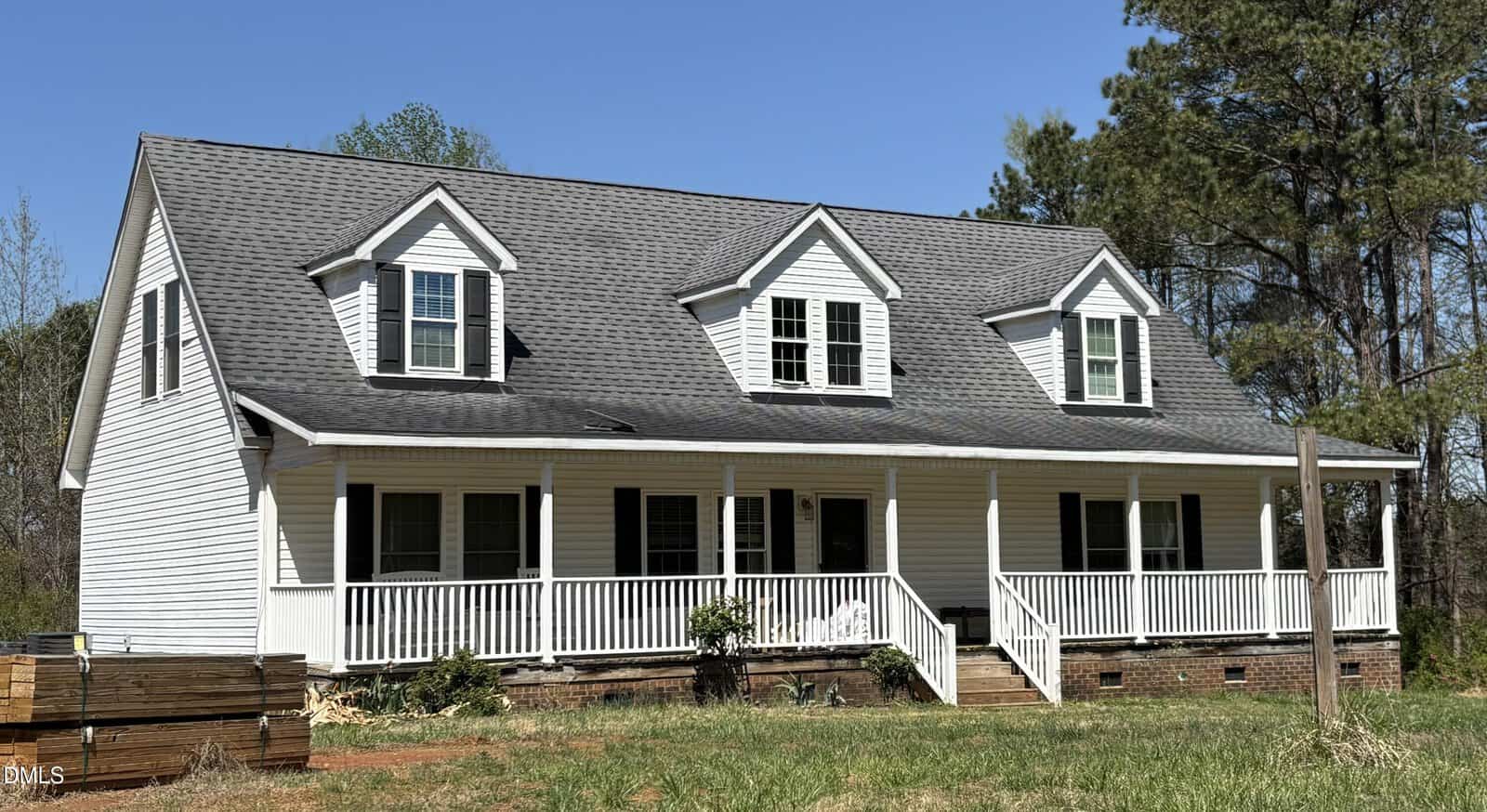 A white two-story house with gray shingles, black shutters, three dormer windows, and a large covered front porch sits at 344 J B Leonard Road in Castalia. Surrounded by grass, trees, and a clear blue sky, this charming home offers inviting curb appeal in a tranquil setting.