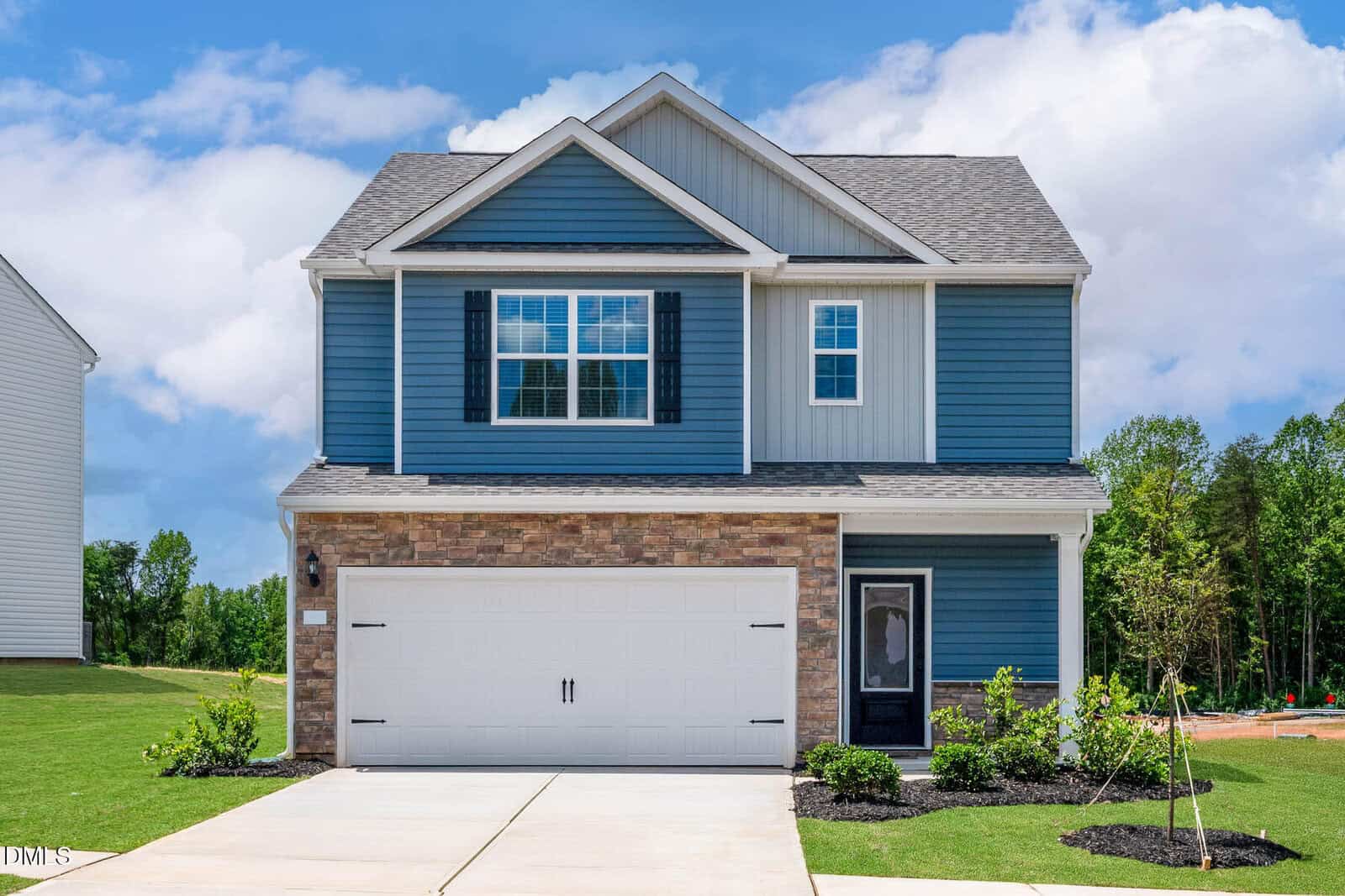Charming two-story blue house with white trim located at 1122 Rhino Bend, Oxford. Features include a large front window, brick accent on the lower half, white double garage door, small front porch, green lawn, and a clear blue sky in the background.
