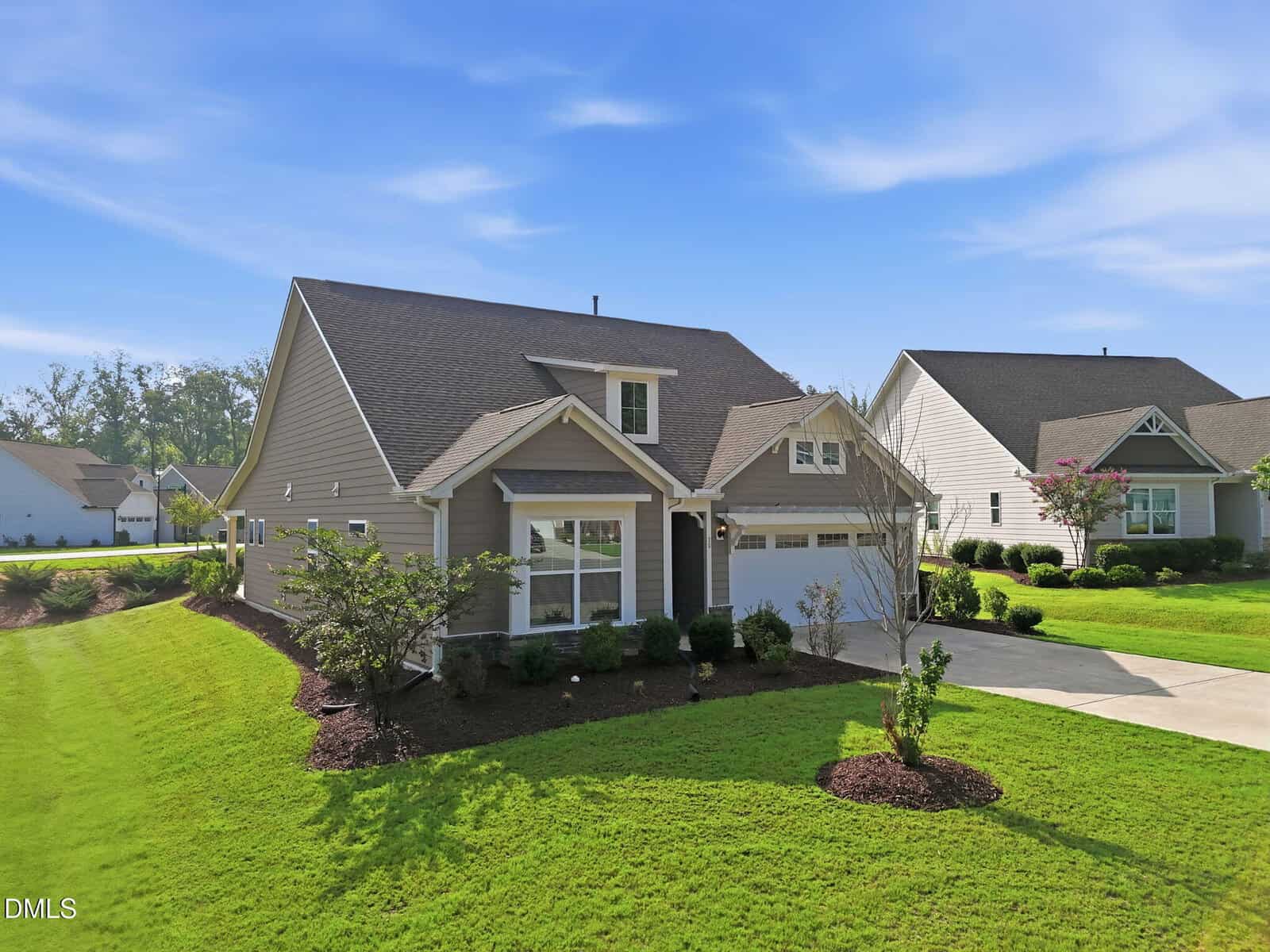A modern single-story suburban house at 30 Bramblewood Drive in Youngsville features beige siding, a gabled roof, attached garage, manicured lawn, shrubs, and a clear blue sky in the background.