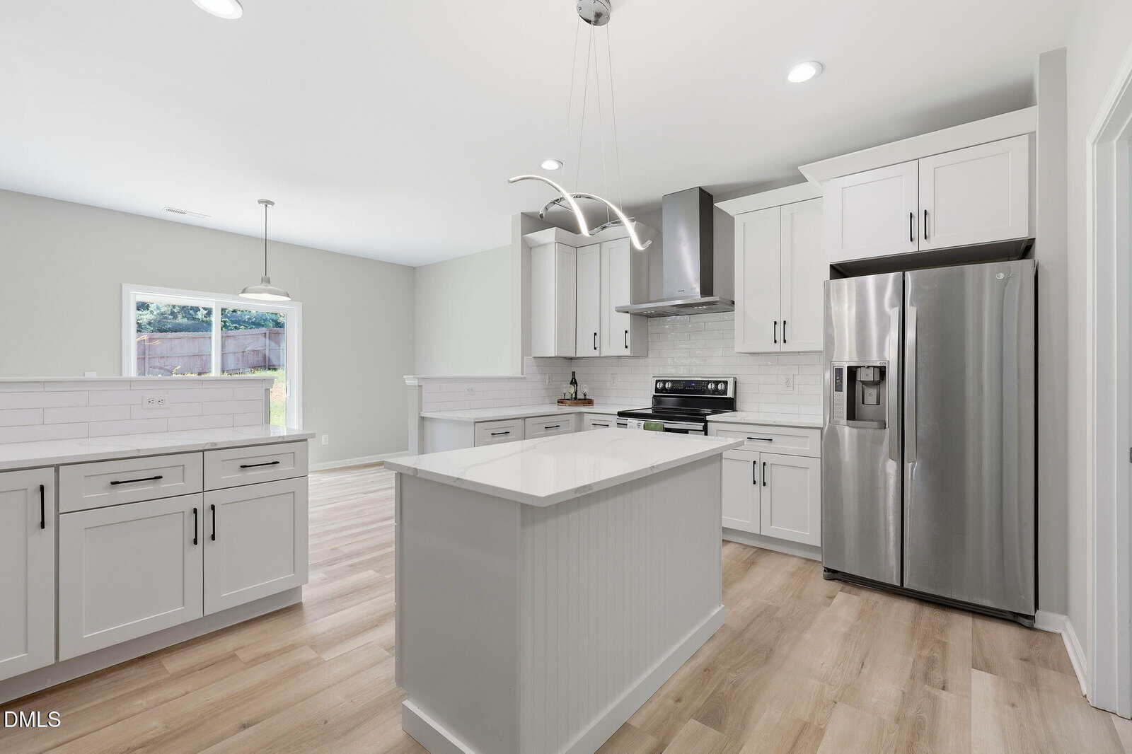 Modern kitchen with white cabinets, a central island, stainless steel appliances, light wood flooring, and a window letting in natural light. Sleek design with minimalist fixtures and bright, clean surfaces.