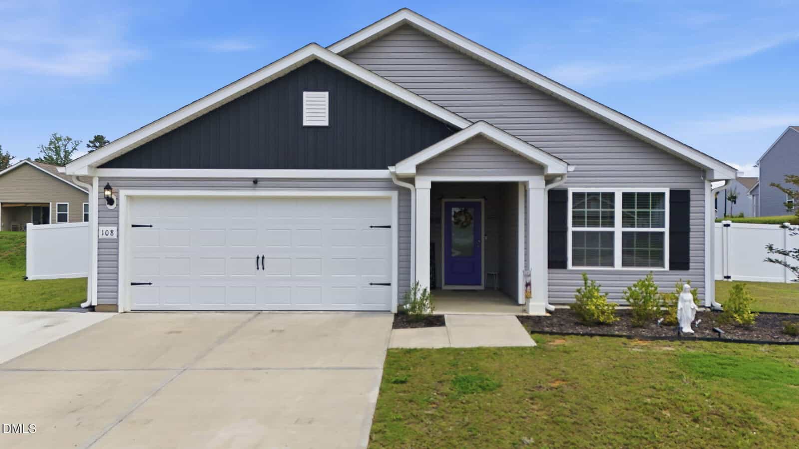Single-story gray house at 108 Anaheim Street, Oxford, featuring a black gable, white garage door, and purple front door. There's a small covered porch, landscaped front yard, and a concrete driveway under a blue sky.