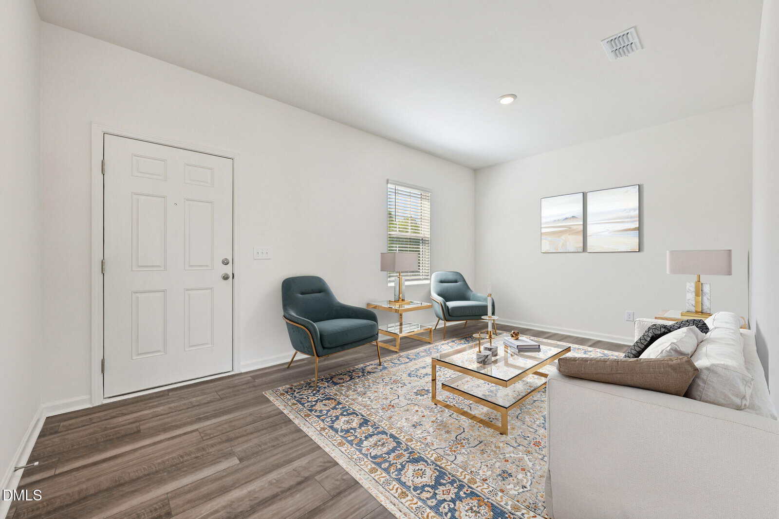 Bright living room with two green armchairs, a white sofa, two side tables with lamps, a coffee table, and a patterned rug on wood flooring. Light walls and a window let in natural light.