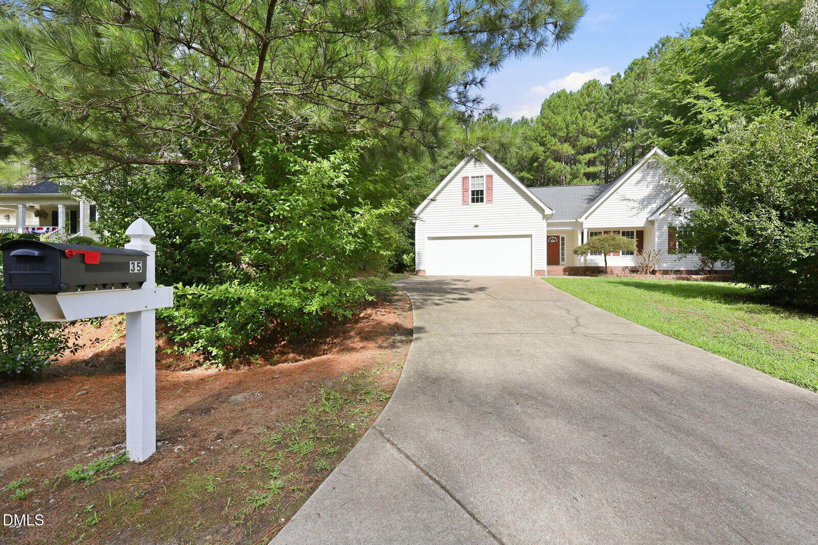 A white mailbox marked "35" stands by a curved driveway leading to a white house with a porch, surrounded by green trees and bushes on a sunny day at 35 Abbington Place in Youngsville.