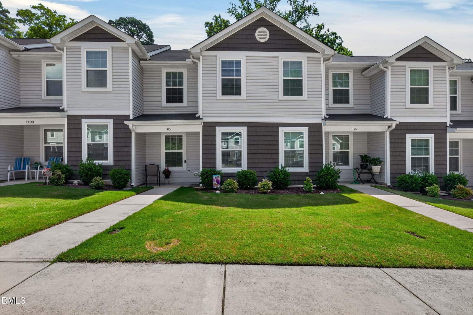 Charming two-story townhouse in Franklinton featuring gray siding and white trim, a manicured front lawn, neatly trimmed shrubs, and a covered entryway. A paved walkway leads from the sidewalk to the front door at 918 E Green Street.