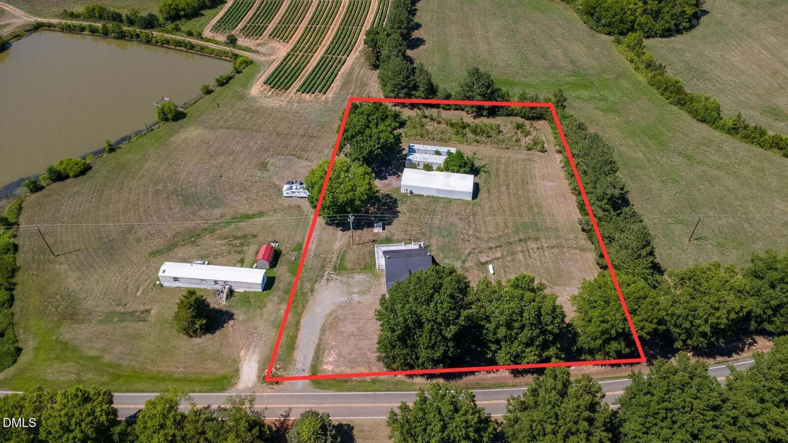 Aerial view of the rural property at 1509 Oak Hill Road, Oxford, outlined in red, featuring several buildings, trees, open grassy areas, nearby farmland, a pond, and a surrounding road.