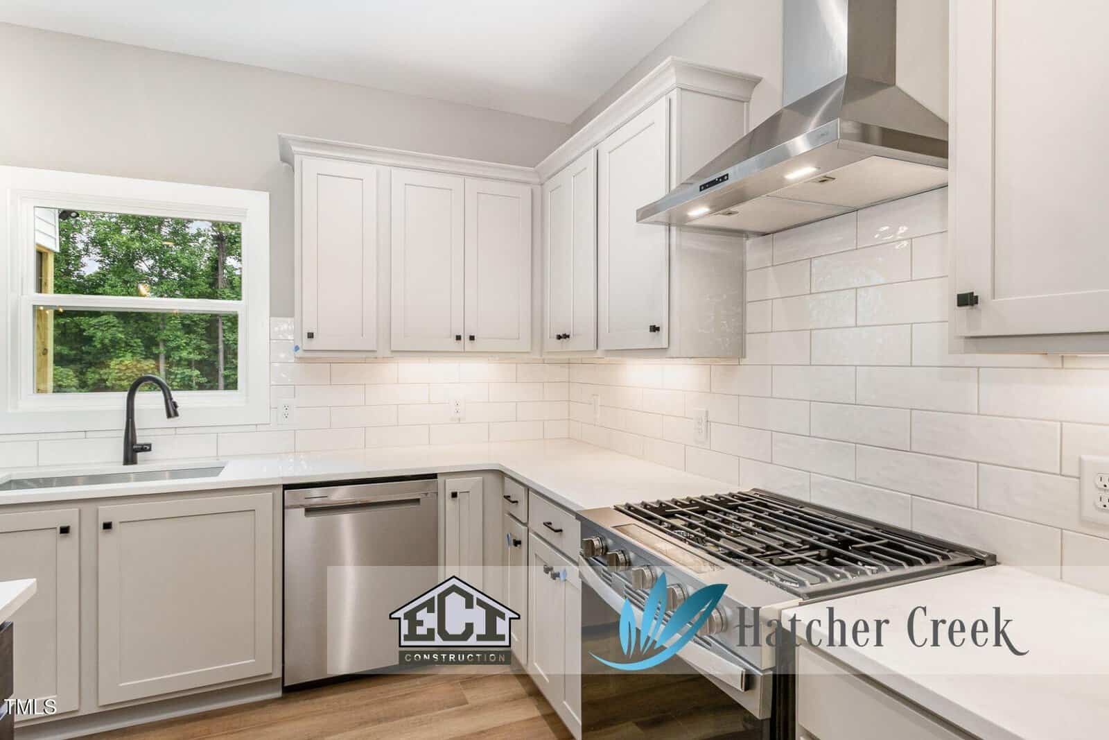 Modern kitchen with white cabinets, stainless steel appliances, gas stove, subway tile backsplash, window above the sink, and bright lighting. ECI Construction and Hatcher Creek logos are overlaid at the bottom.