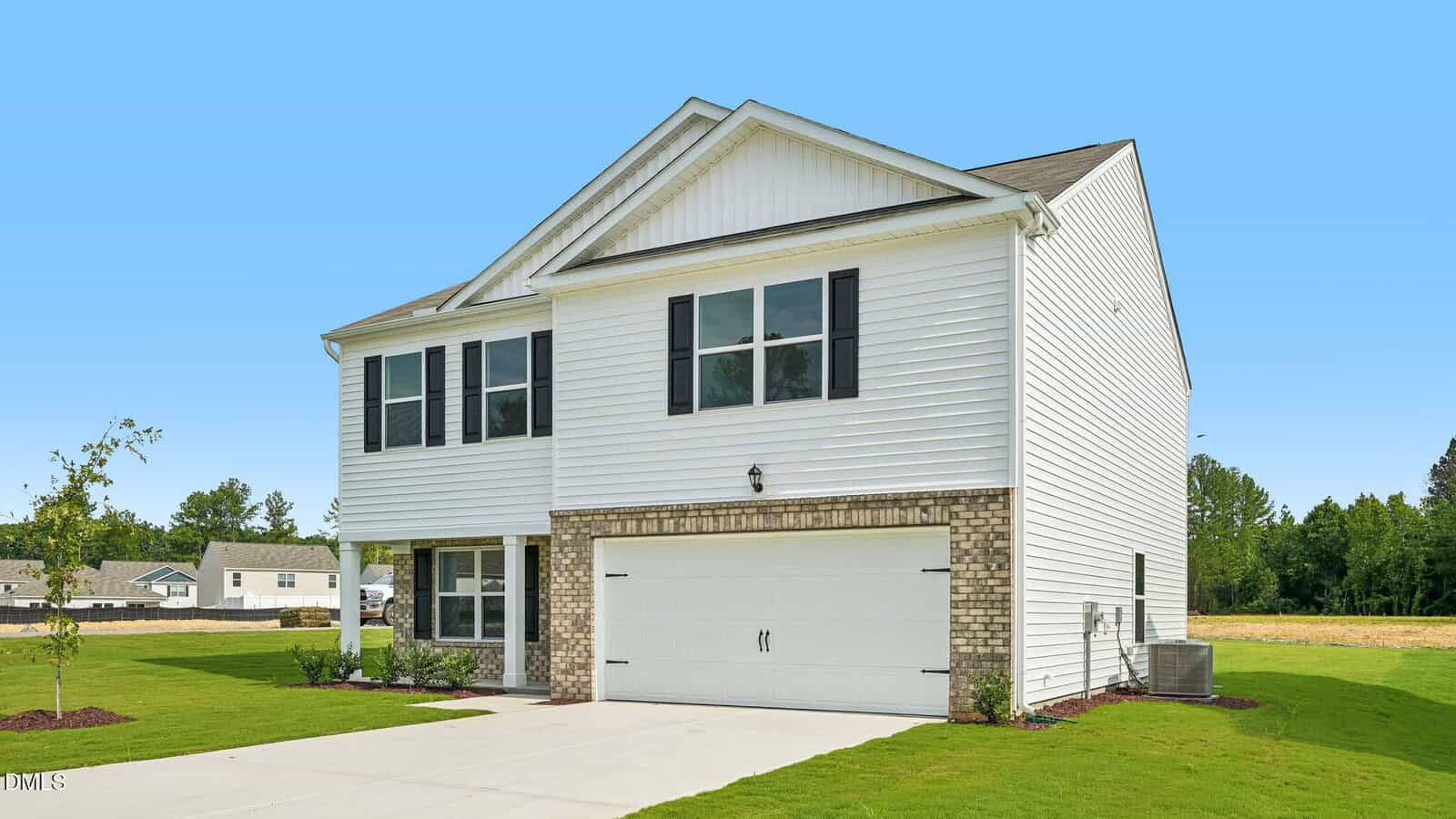 Two-story white house with brick accents, black shutters, and a double garage. The home is surrounded by a green lawn and is set against a clear blue sky.