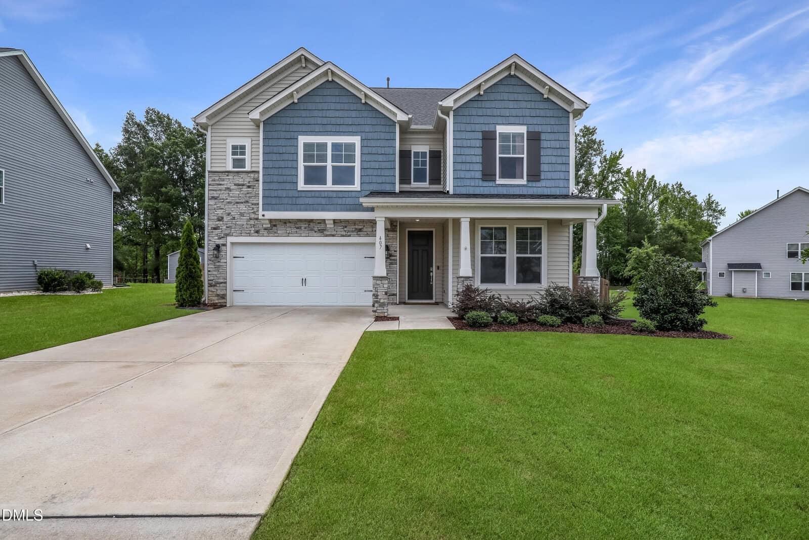 Two-story suburban house at 407 Porter Hill Drive in Youngsville, featuring blue siding, gray stone accents, white trim, a double garage, and a covered front porch. The home is surrounded by green grass and landscaped bushes with trees in the background.