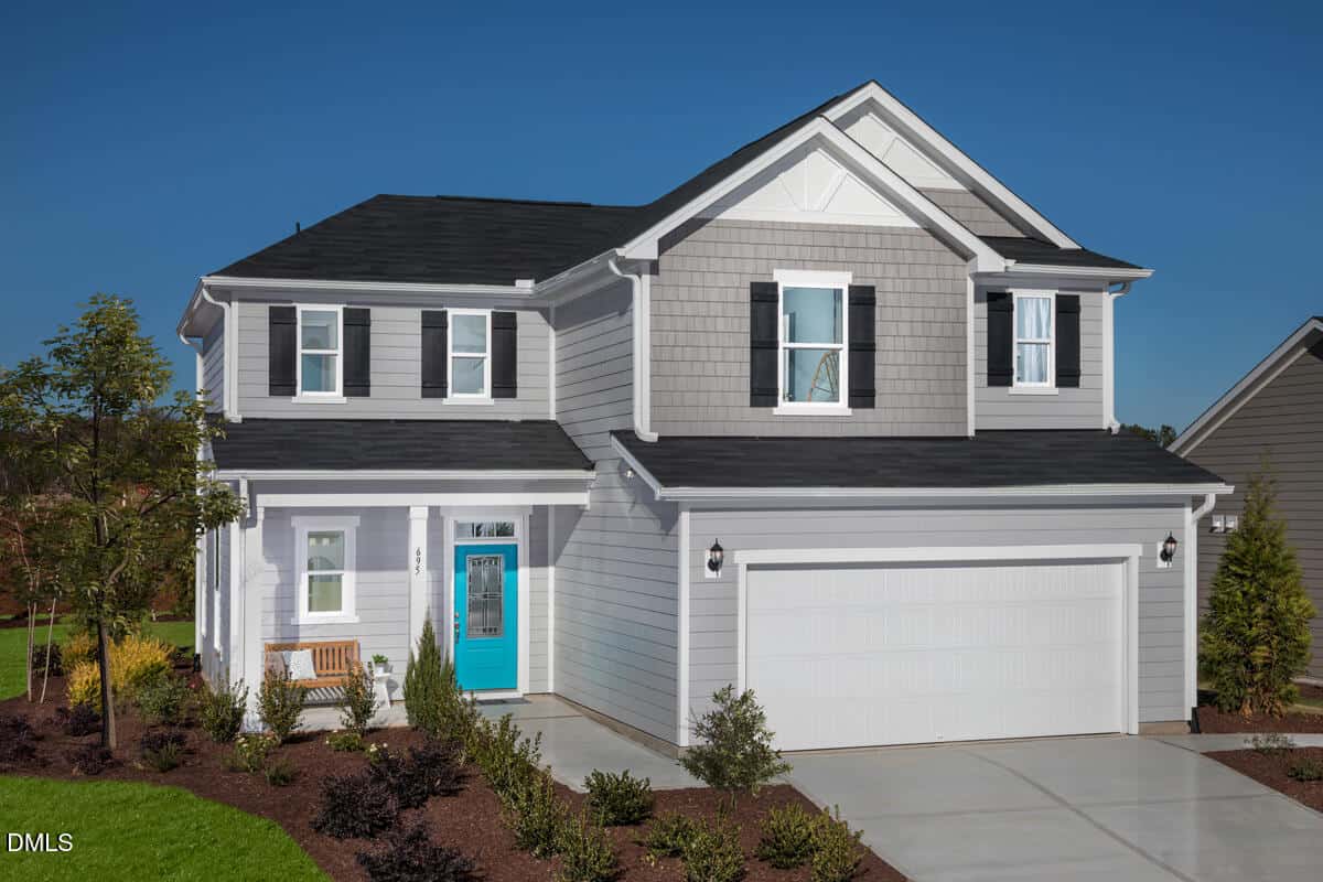 Two-story gray suburban house with white trim, black shutters, and a bright blue front door located at 695 Purple Aster Street in Youngsville. There is a double garage, a small front porch with a bench, a concrete driveway, and landscaping with shrubs and trees.