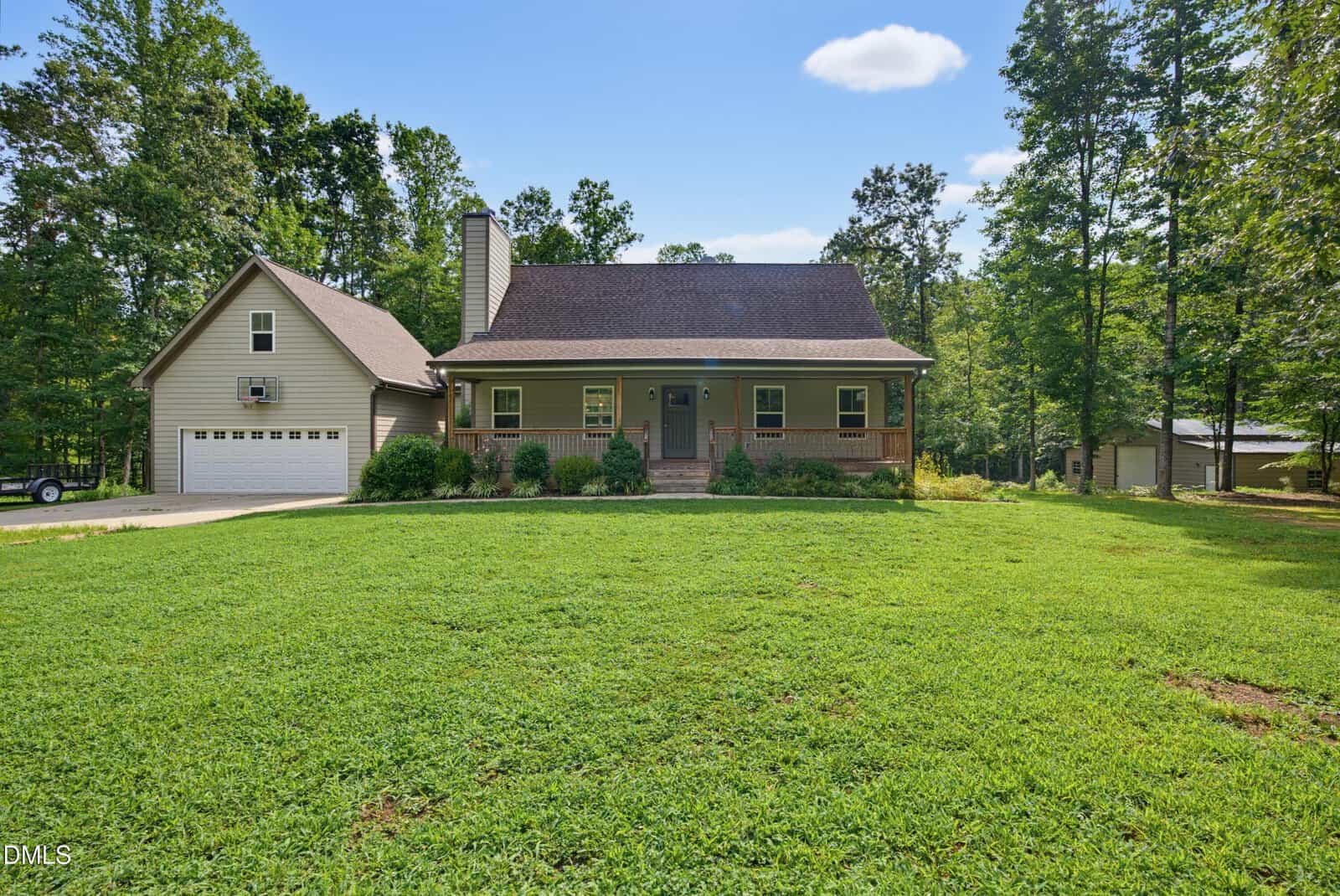 A single-story house with a covered front porch, attached garage, and large grassy yard located at 95 Birch Creek Farm Lane in Franklinton. The home is surrounded by trees and has a wide driveway leading to the garage. The sky is mostly clear with a few clouds.