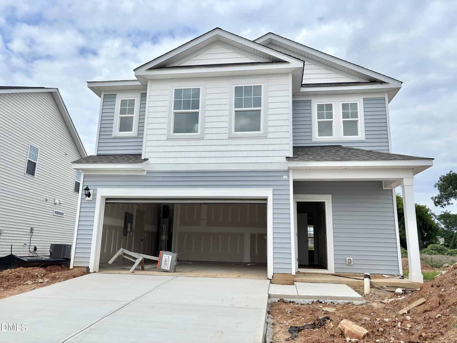 A two-story, light blue house with white trim, an attached two-car garage, and a driveway sits at 12 Gerrard Street in Franklinton. The garage doors are open, exposing the unfinished interior. The yard and surroundings appear under construction.