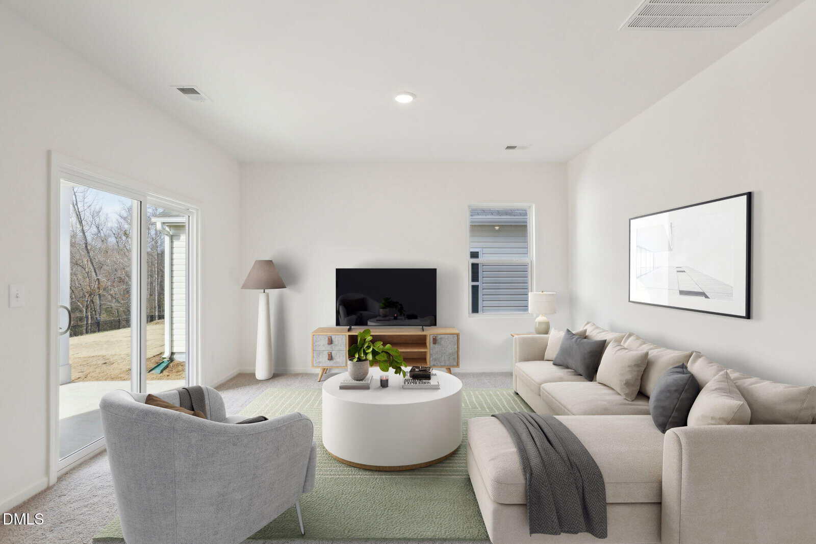 A modern living room with a beige sectional sofa, gray armchair, round white coffee table, and TV on a wooden stand. Sliding glass doors open to a patio, and a large window lets in natural light. Minimalist decor and wall art are present.