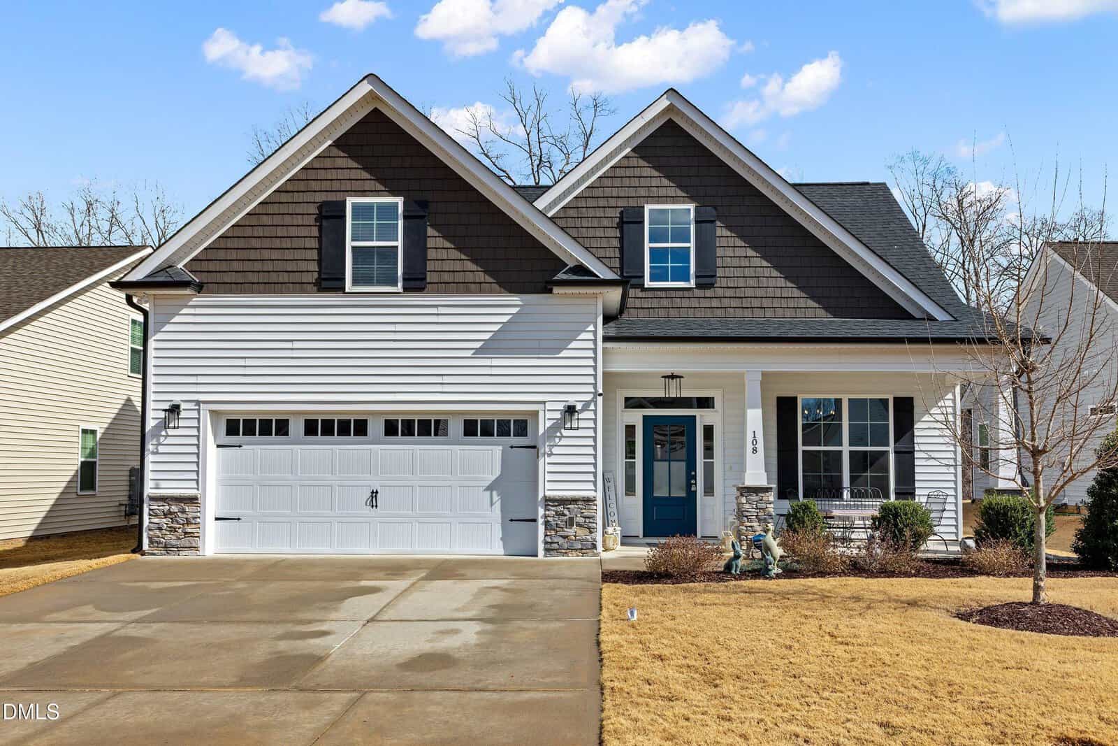 A modern two-story suburban house located in Youngsville at 108 Sweetbay Park, featuring a two-car garage, stone and siding exterior, blue front door, shuttered windows, a small front porch, and a neatly maintained lawn. Trees are visible in the background.