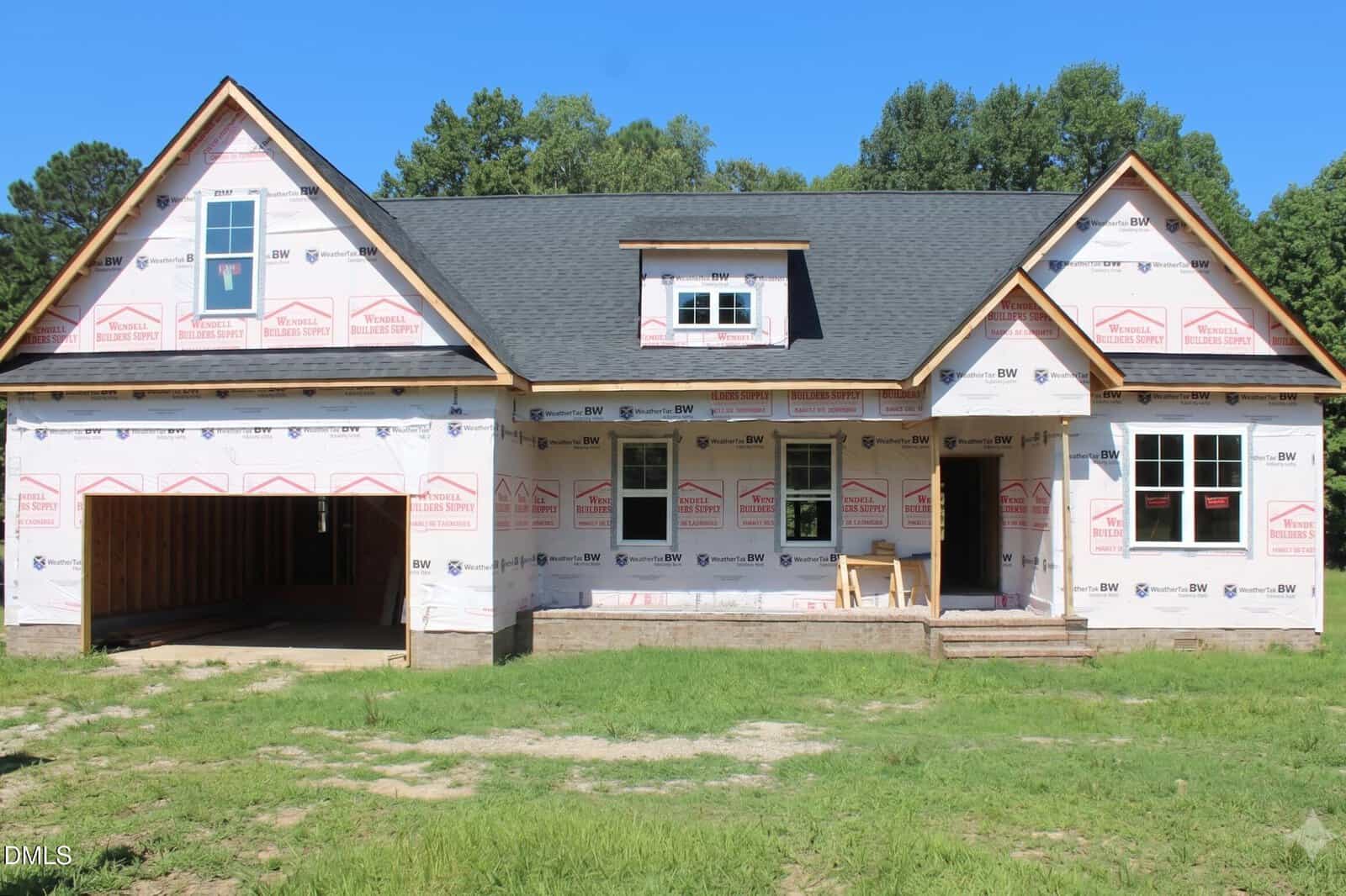 A partially constructed house at 20 Home Place Lane in Zebulon features visible roof shingles, an attached garage, and exterior walls covered in weather-resistant sheeting. There are no windows or doors installed yet, and the front yard has grass and dirt patches.