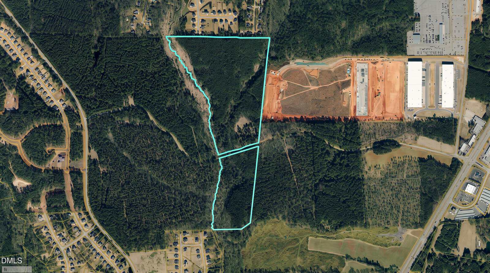 Aerial view of a forested area with three land parcels outlined in blue. Surrounding areas include residential neighborhoods, industrial buildings, and construction zones. Roads and other infrastructure are visible.