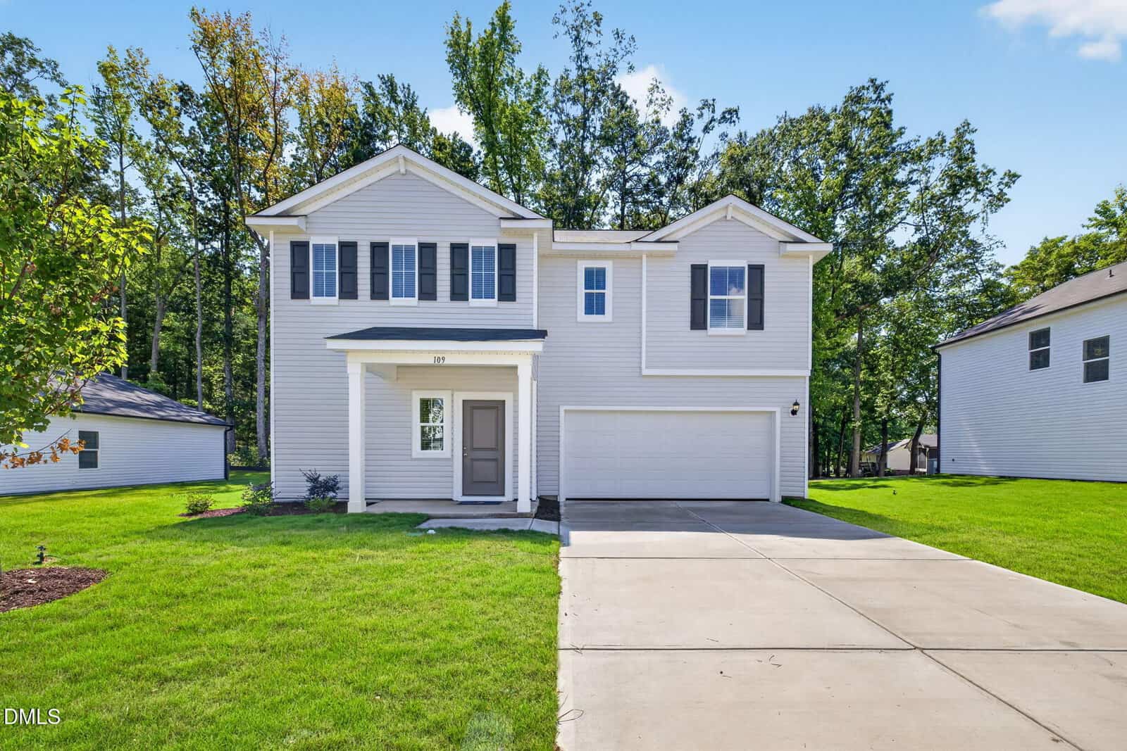 Two-story, light gray suburban house with white trim, double garage, a driveway, and green lawn located at 109 Airdale Drive in Oxford. Trees and clear blue sky in the background.