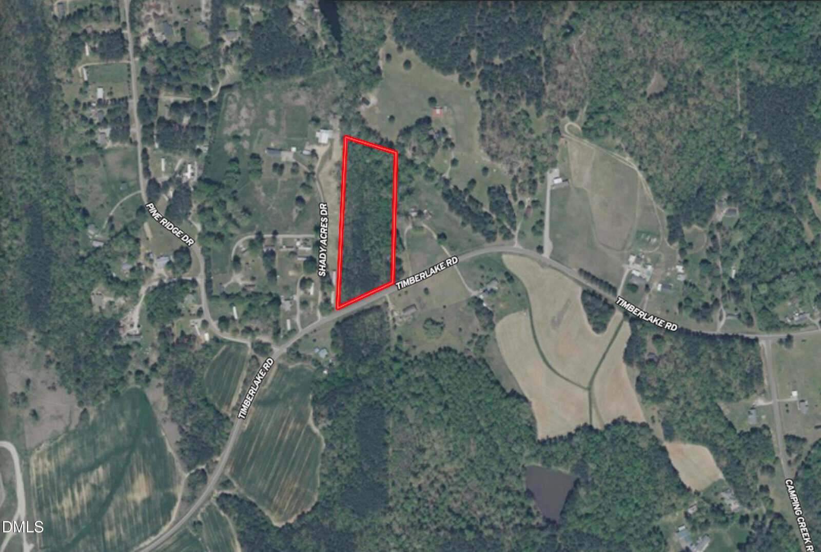 Aerial view of a rural area with homes, roads, and trees. A large, irregular rectangular plot of land is outlined in red near Timberlake Road and Sandy Branch Drive.