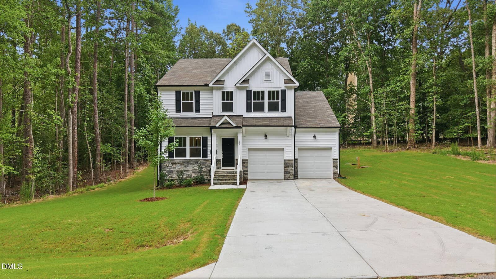 Two-story suburban house with white siding, gray stone accents, a covered front porch, and a double garage located at 100 Chanute Circle in Louisburg. Concrete driveway and well-kept lawn; the home is surrounded by tall trees and dense greenery.