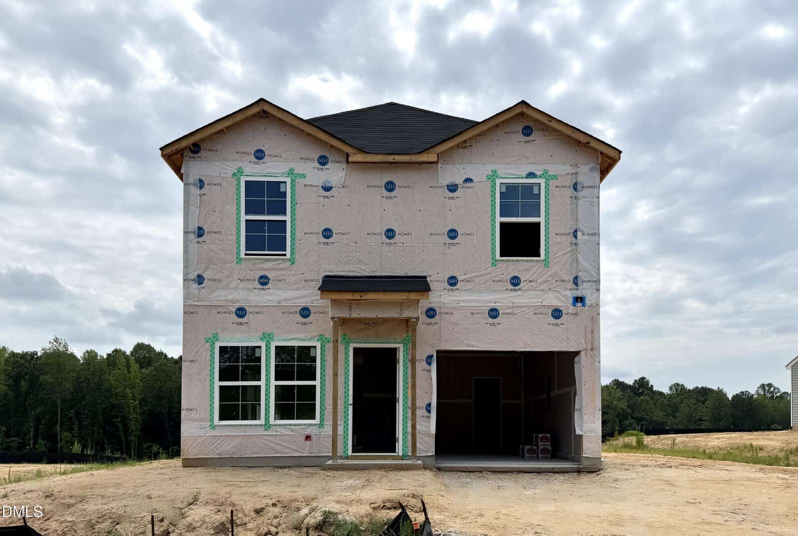 A two-story house under construction at 275 Buckthorn Drive, Youngsville, wrapped in protective sheeting, with exposed window frames and an open garage. The yard is bare dirt, and trees are visible in the background under a cloudy sky.