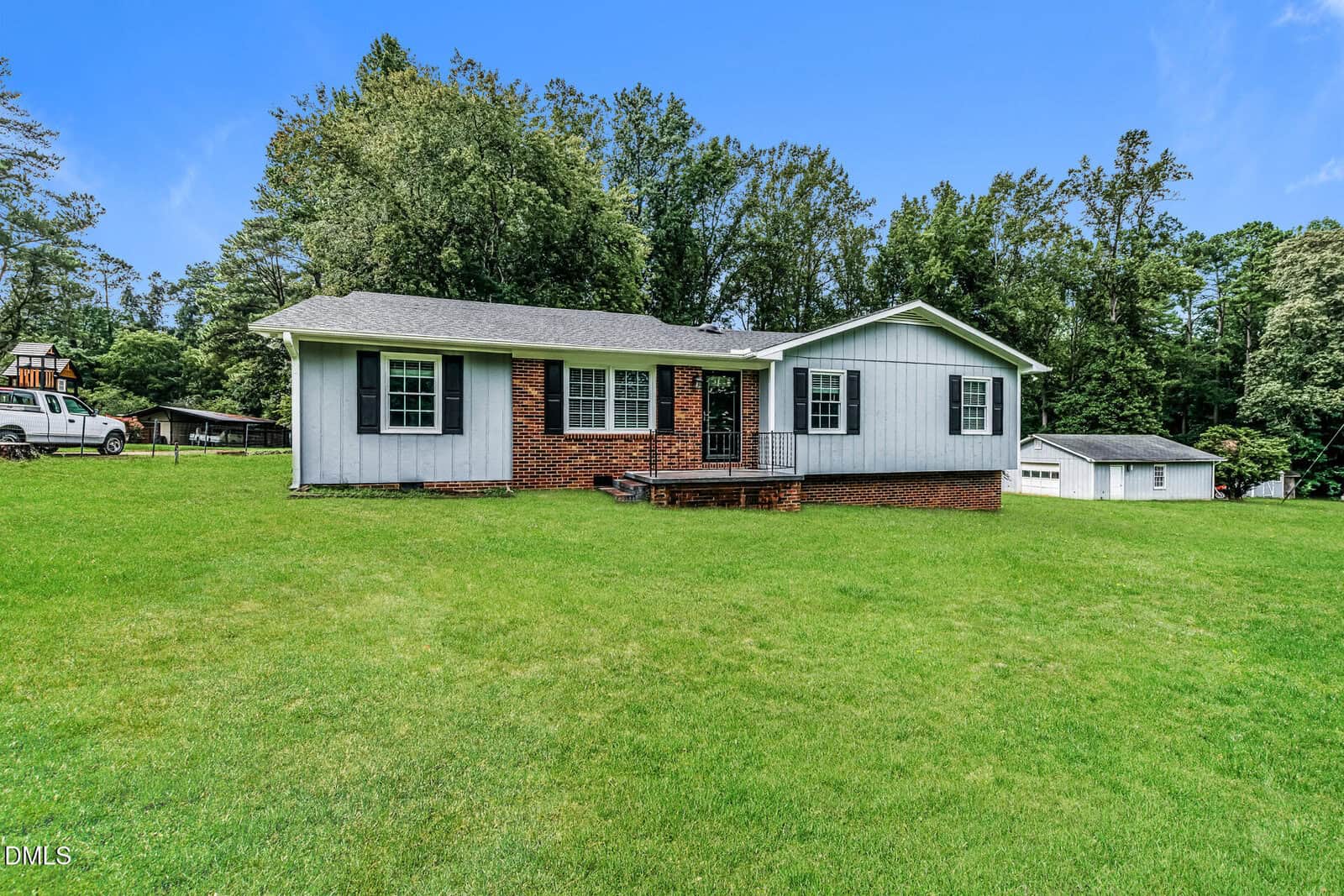 Single-story house with gray siding and red brick foundation, set on a large grassy yard with trees in the background and a detached garage visible to the right, located at 4685 Dorsey Road in Oxford.