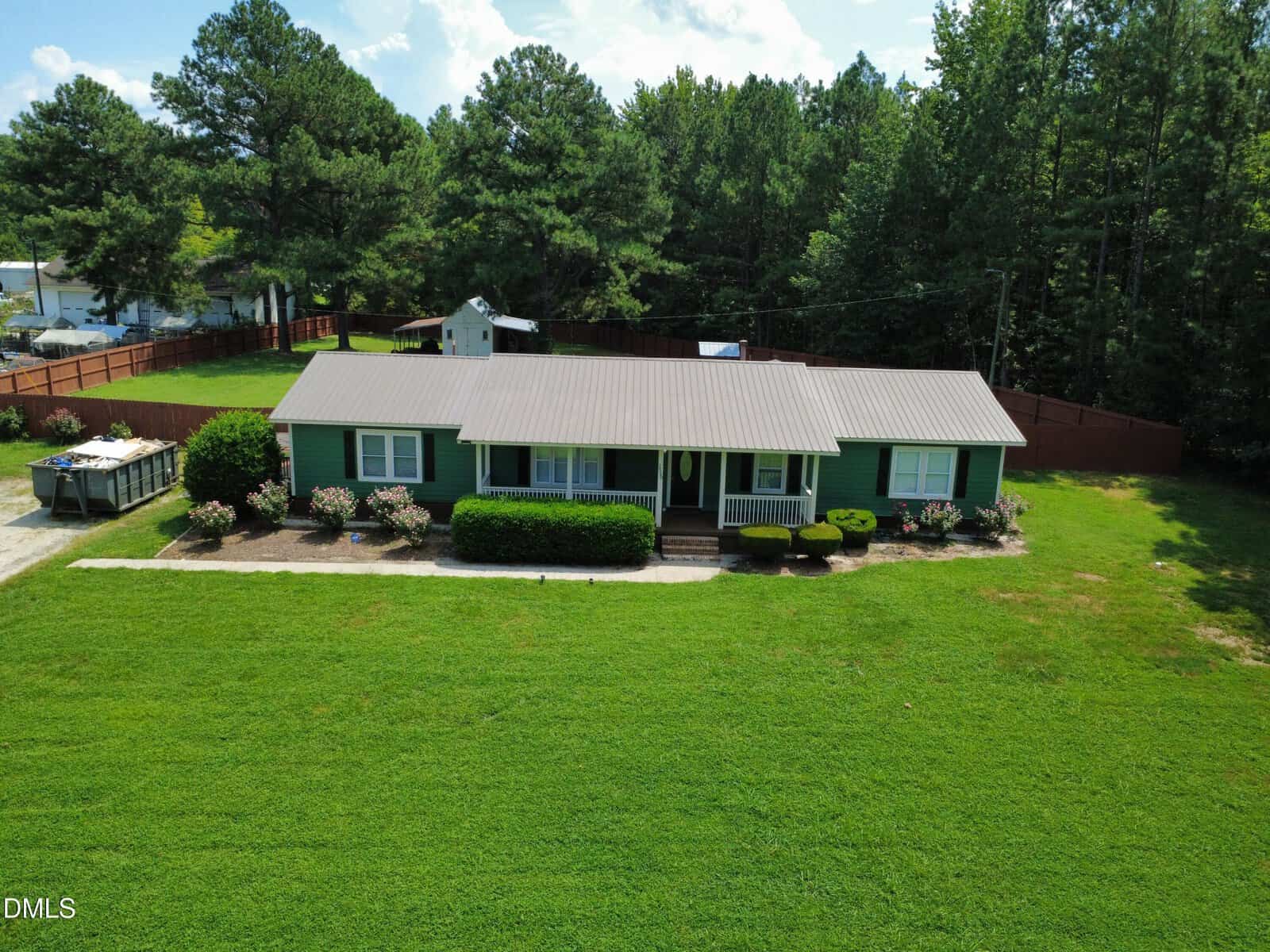 Aerial view of a single-story green house with a metal roof at 2520 Conyers Road, Franklinton, surrounded by a large, well-kept lawn, bushes, and trees. A fenced backyard and a shed are visible in the background.
