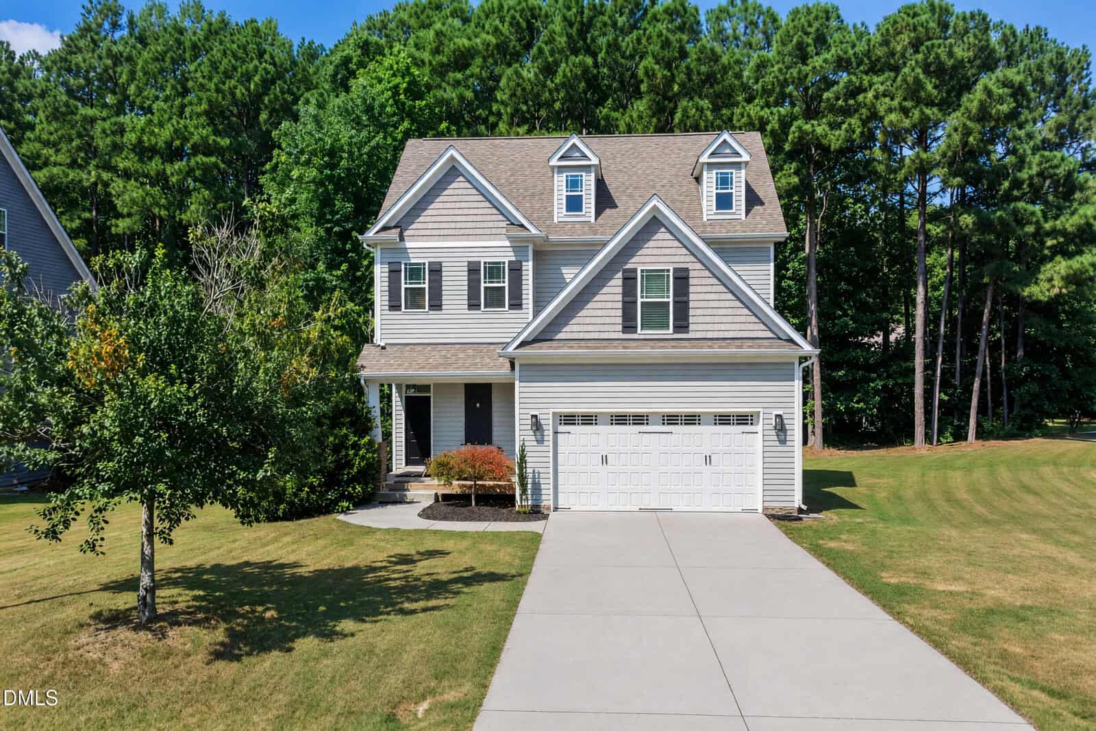 Two-story suburban house with gray siding, attached double garage, and front porch at 165 Willow Ridge Drive in Louisburg. Concrete driveway and green lawn, surrounded by trees in the background.